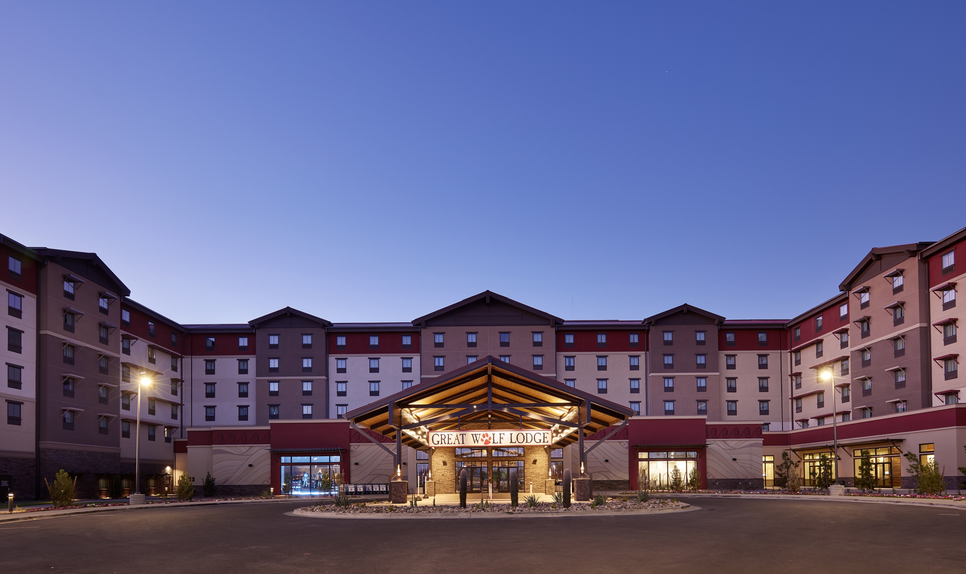 Exterior wide shot of the Great Wolf Lodge Arizona resort at dusk with a lighted entrance portico.