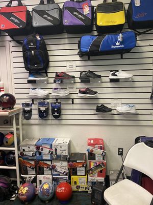 A pro shop display wall featuring colorful bowling bags, several pairs of shoes, and boxed bowling balls.