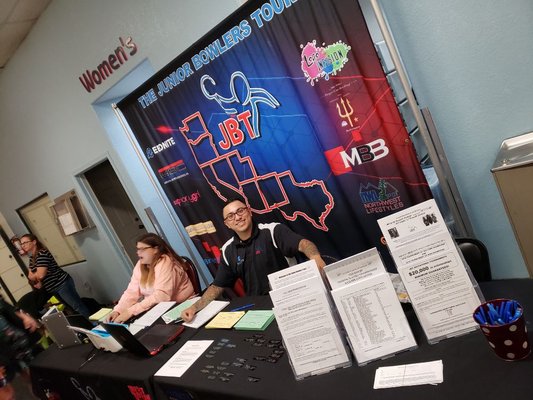 Staff at a registration table for the Junior Bowlers Tour with a branded backdrop and informational flyers.