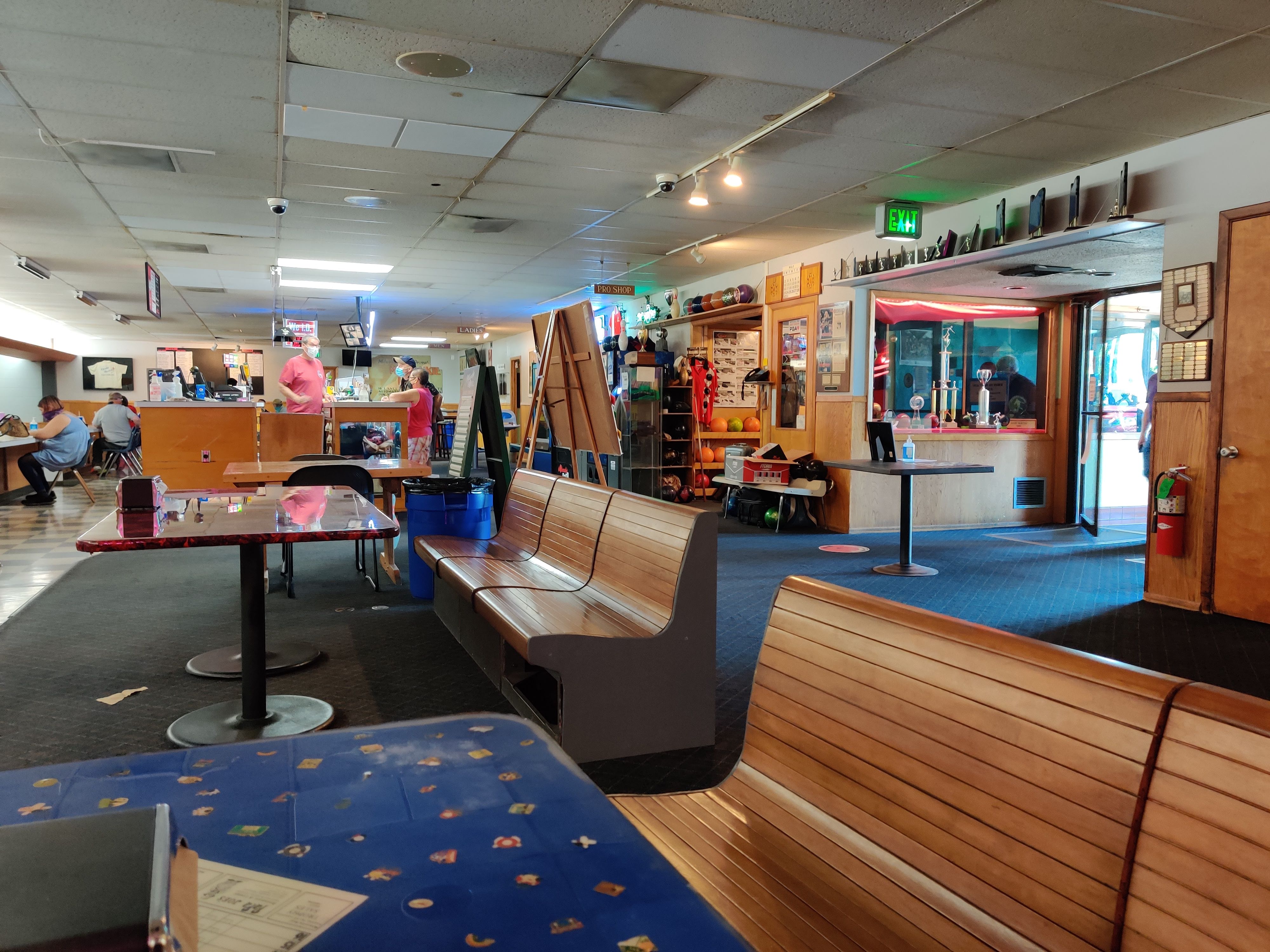 Indoor dining and seating area at a bowling center with wooden benches and patterned tables.