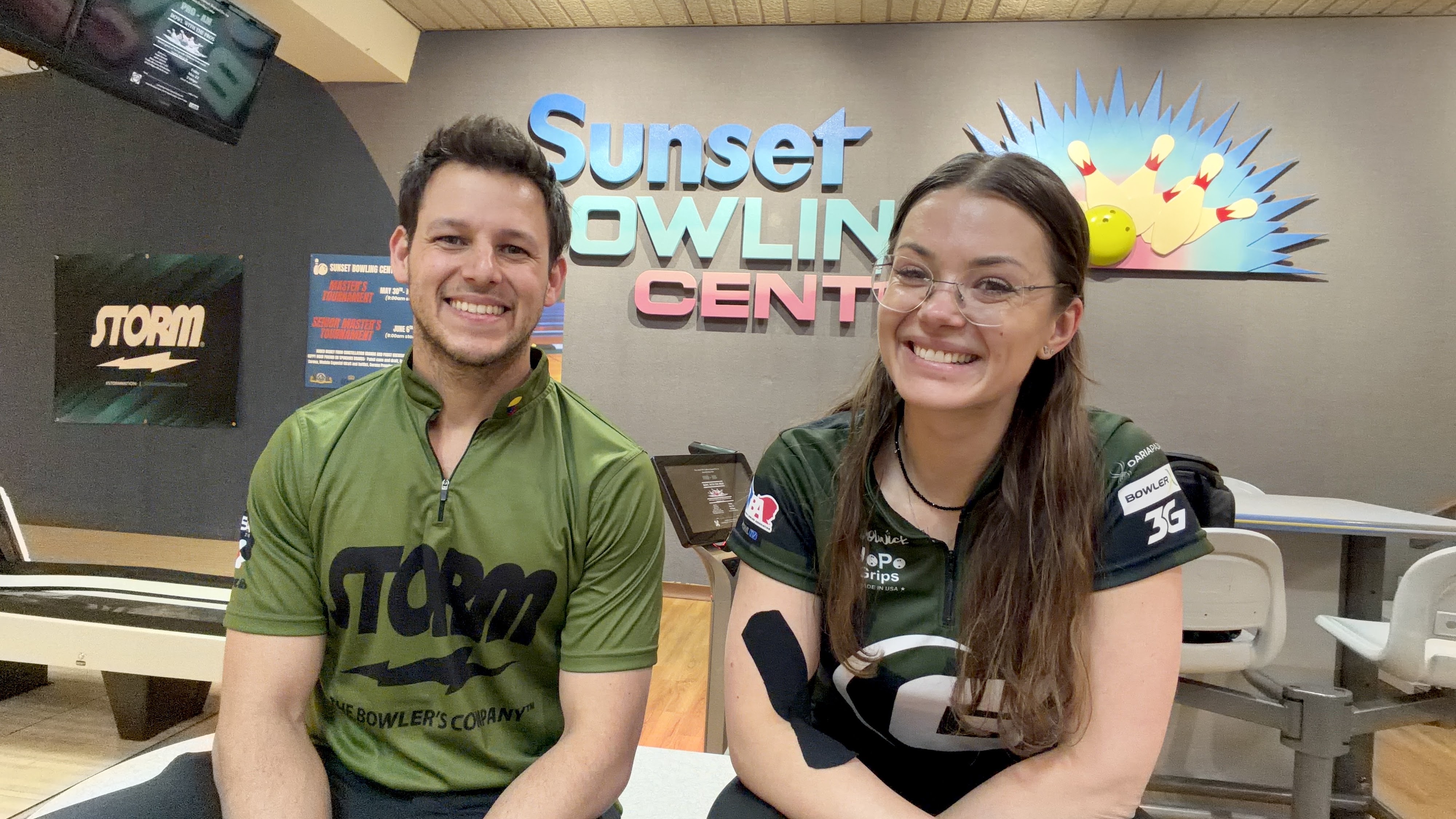 Two people in bowling jerseys smile in front of the Sunset Bowling Center logo.