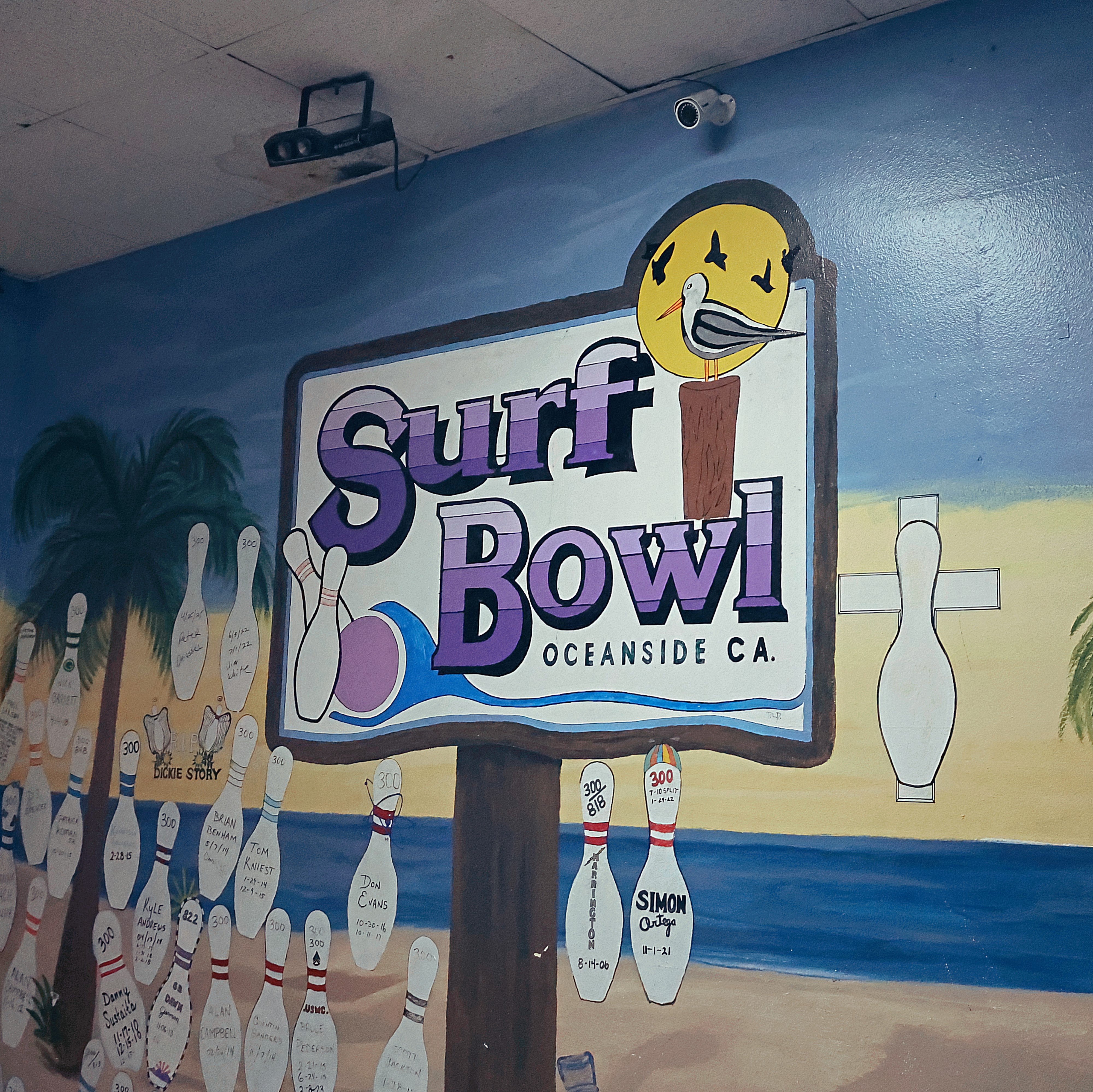 A vibrant wall mural at Surf Bowl in Oceanside featuring a coastal theme and a wall of fame for 300-game bowlers.
