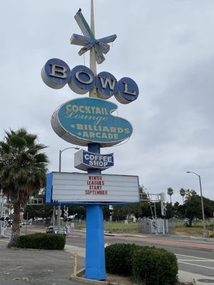 A tall vintage blue and white roadside bowling sign with a marquee announcing winter leagues starting in September.