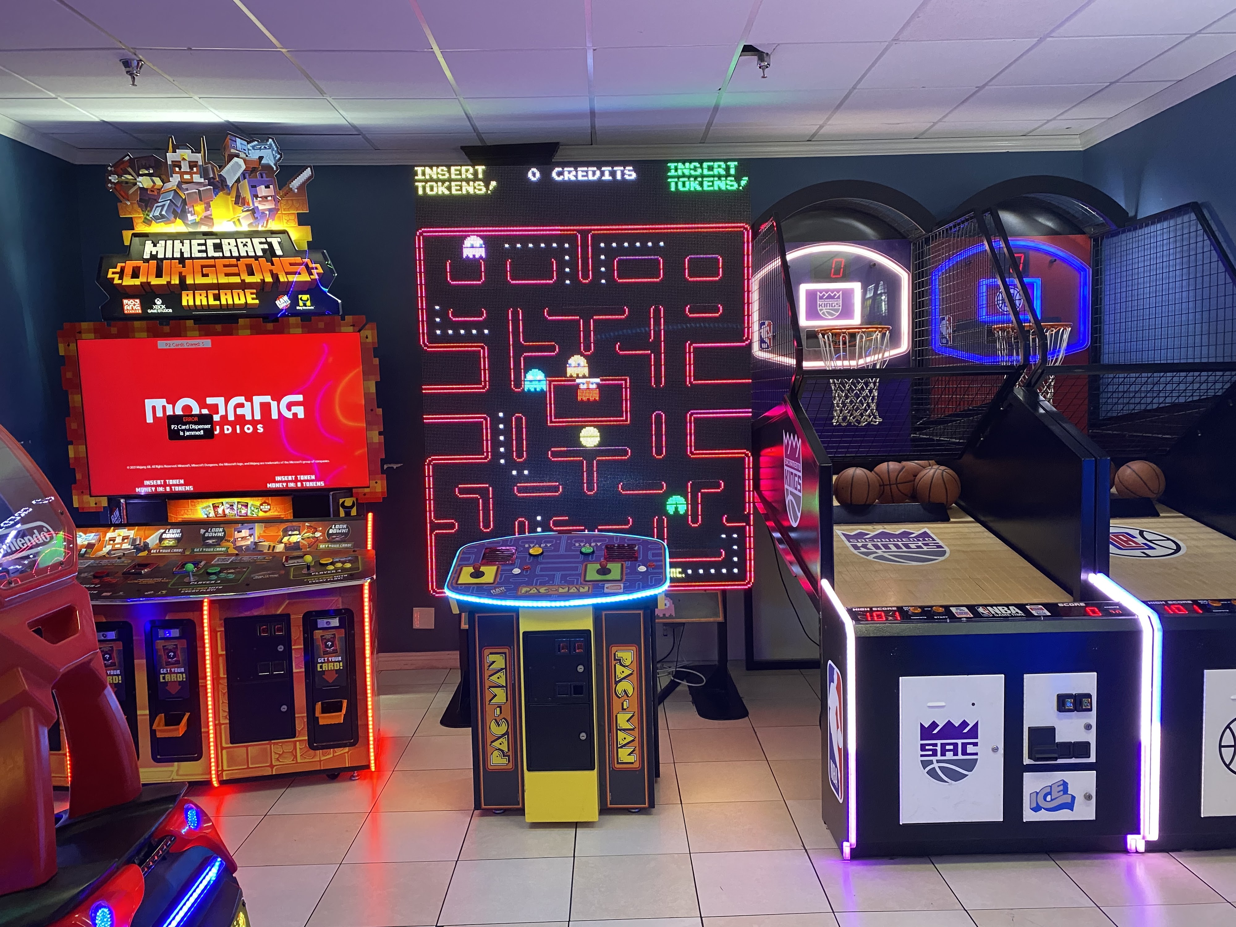 A modern arcade room with a giant Pac-Man game, Minecraft arcade cabinet, and basketball shooting games.