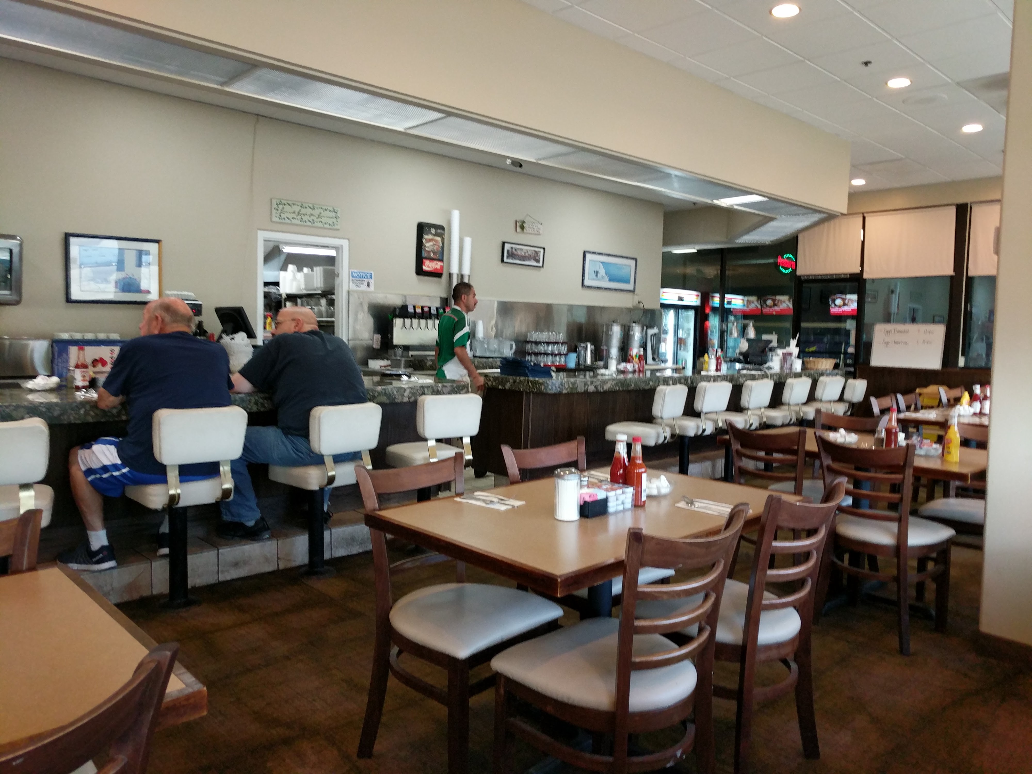 A classic diner interior with a counter, swivel stools, and dining tables inside a bowling center.