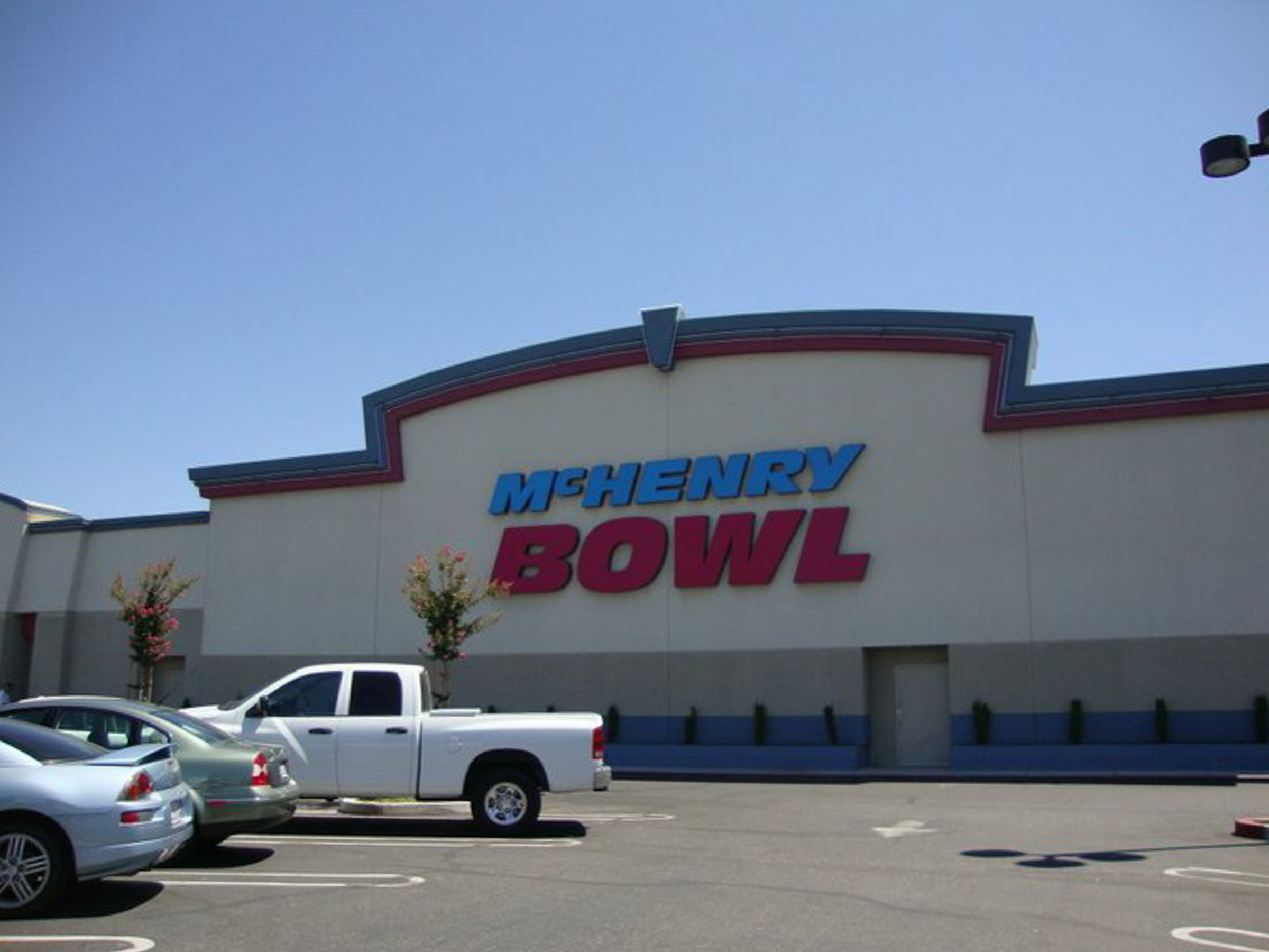 Exterior facade of McHenry Bowl in Modesto with a large red and blue sign under a clear blue sky.