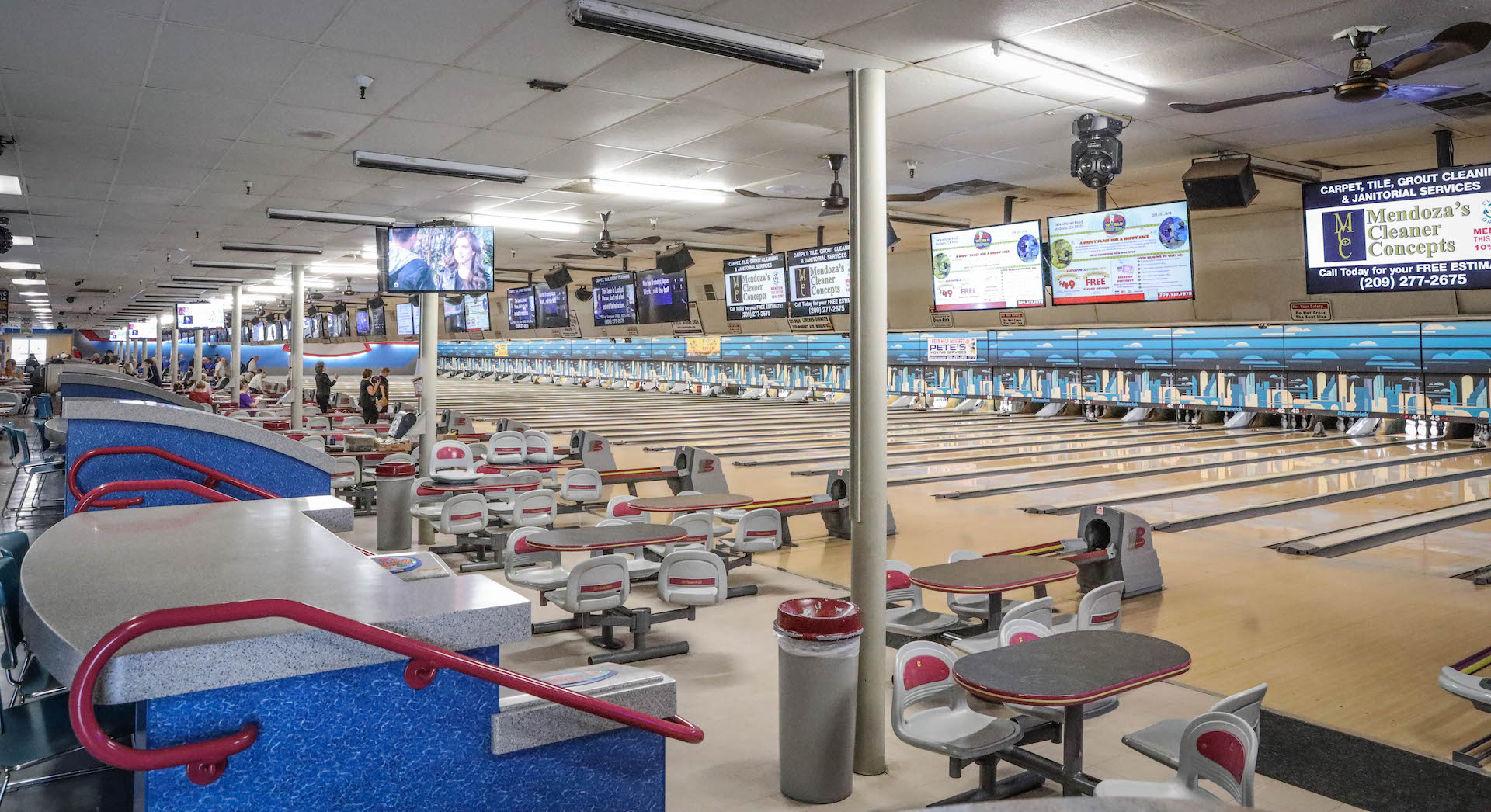 A wide interior view showing several rows of bowling lanes, automatic scoring monitors, and bowler seating areas.