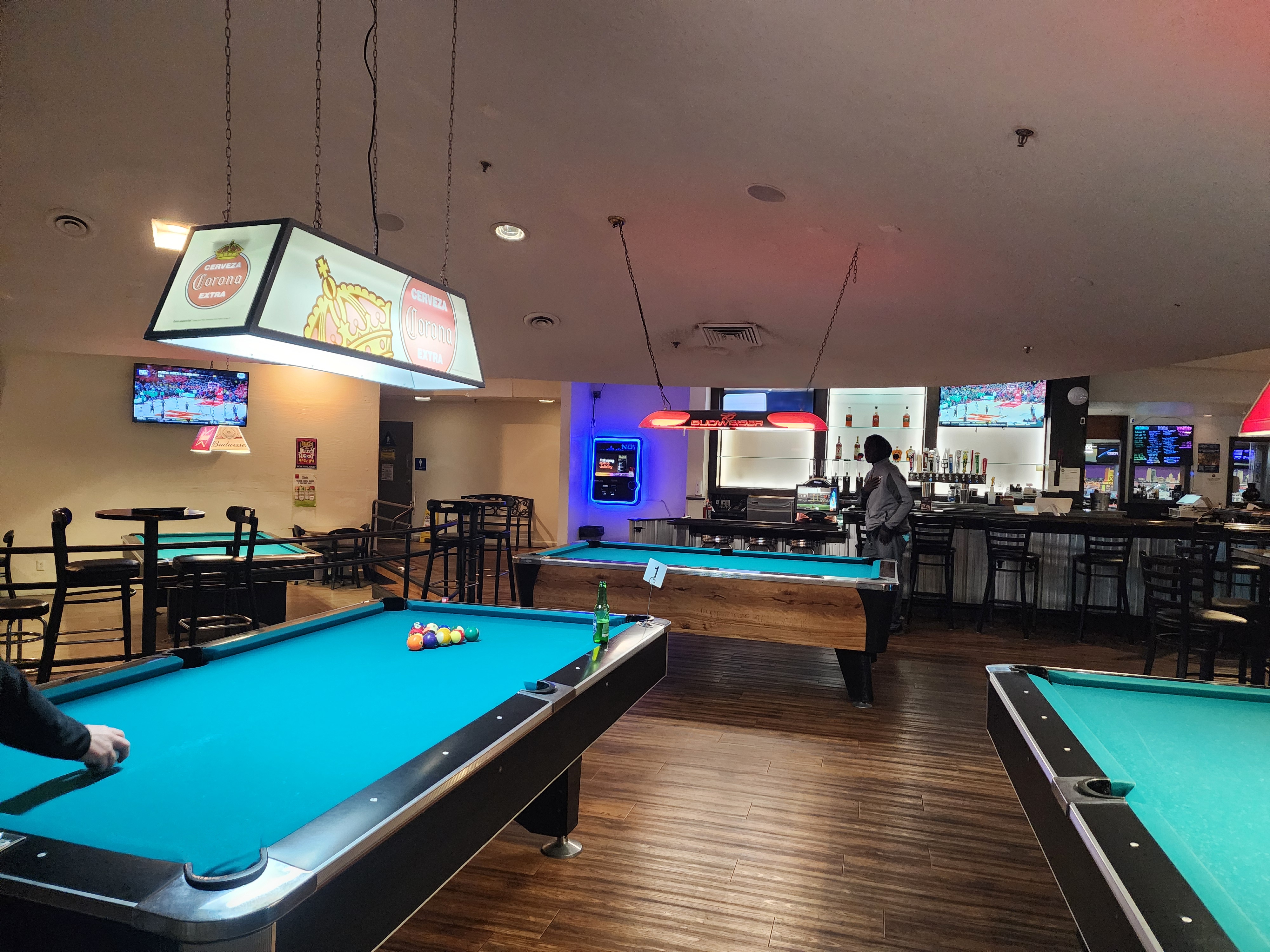 The spacious billiard room at Country Club Lanes with turquoise pool tables and a full bar in the background.