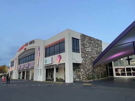 Exterior view of Country Club Lanes bowling center at dusk with neon signage and stone facade.