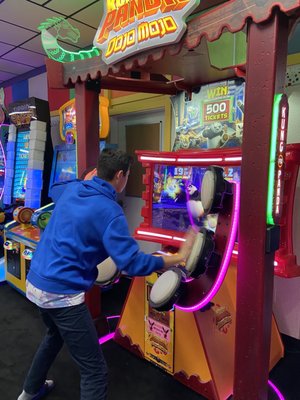 A person plays an interactive Kung Fu Panda arcade game in a brightly lit game room.