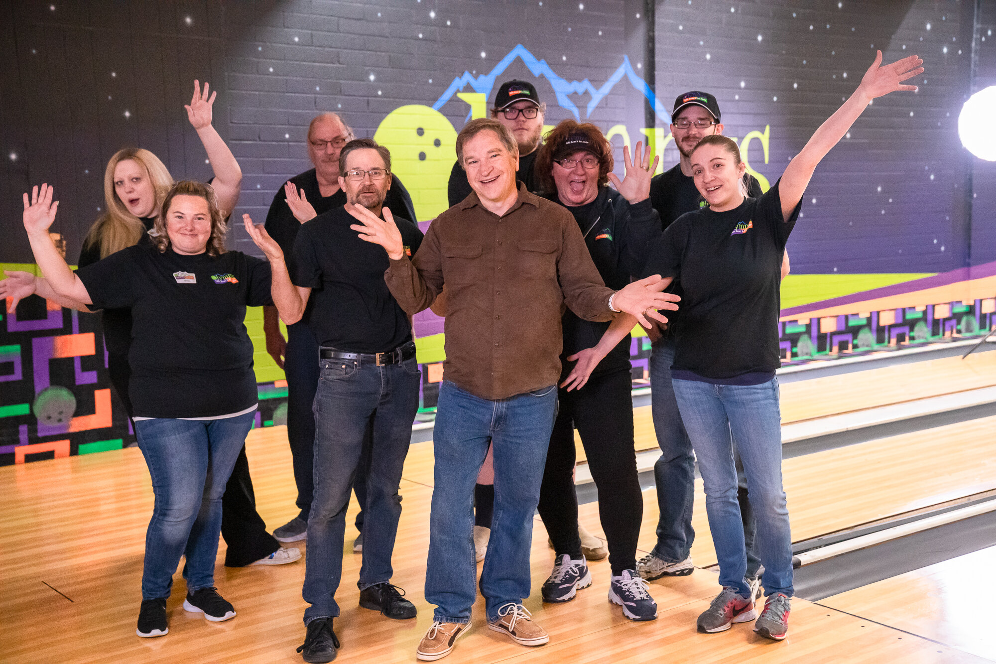A smiling group of staff members posing together on the bowling lanes at Olympus Hills Bowling Lanes.