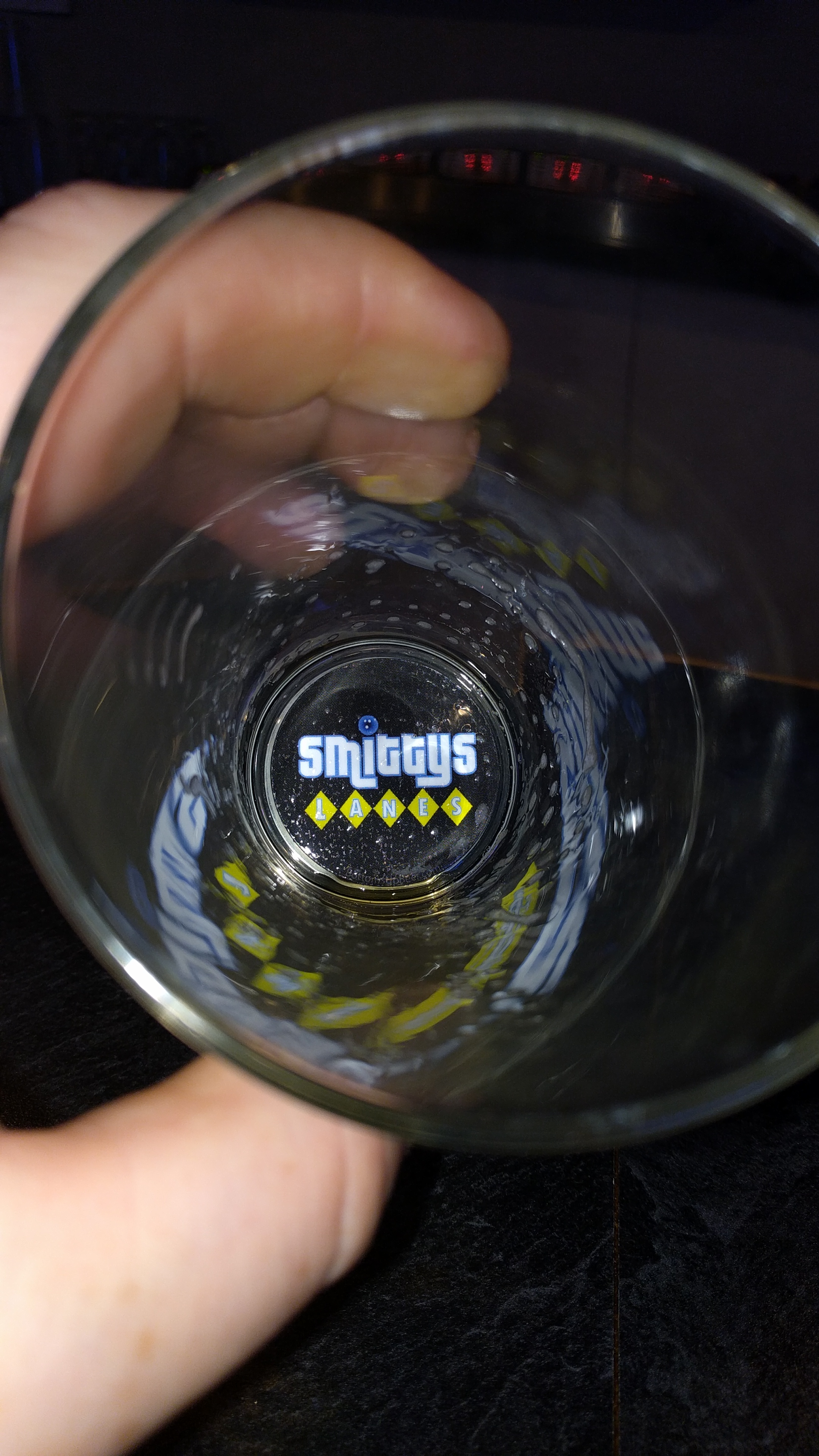 A top-down view inside a drinking glass showing the Smitty's Lanes logo at the bottom.