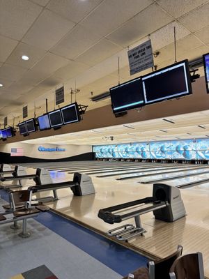 Rows of polished wooden bowling lanes with ball returns and overhead monitors at Westgate Lanes.