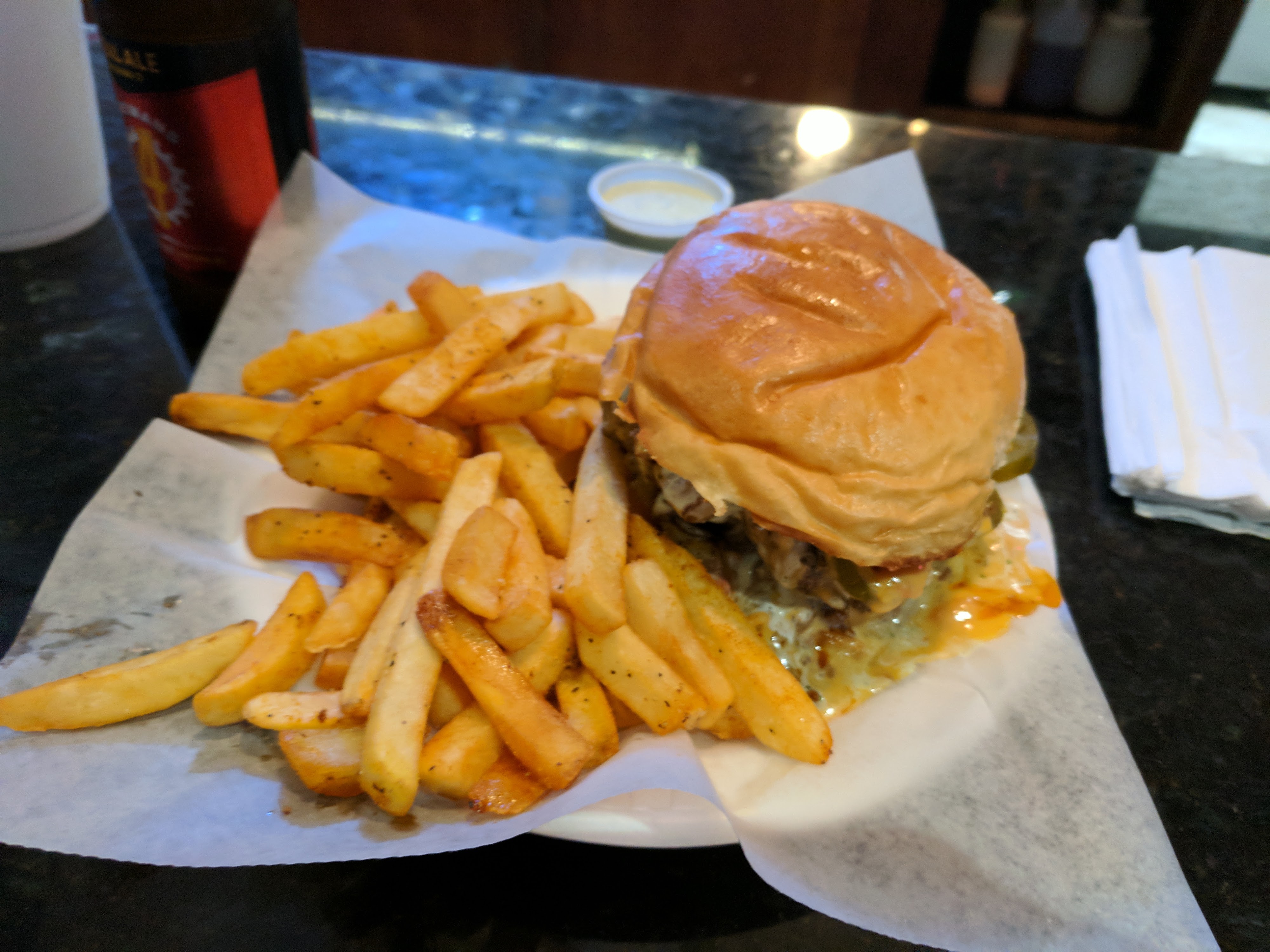 A cheeseburger with melted cheese and jalapeΓ±os served with a side of seasoned french fries.