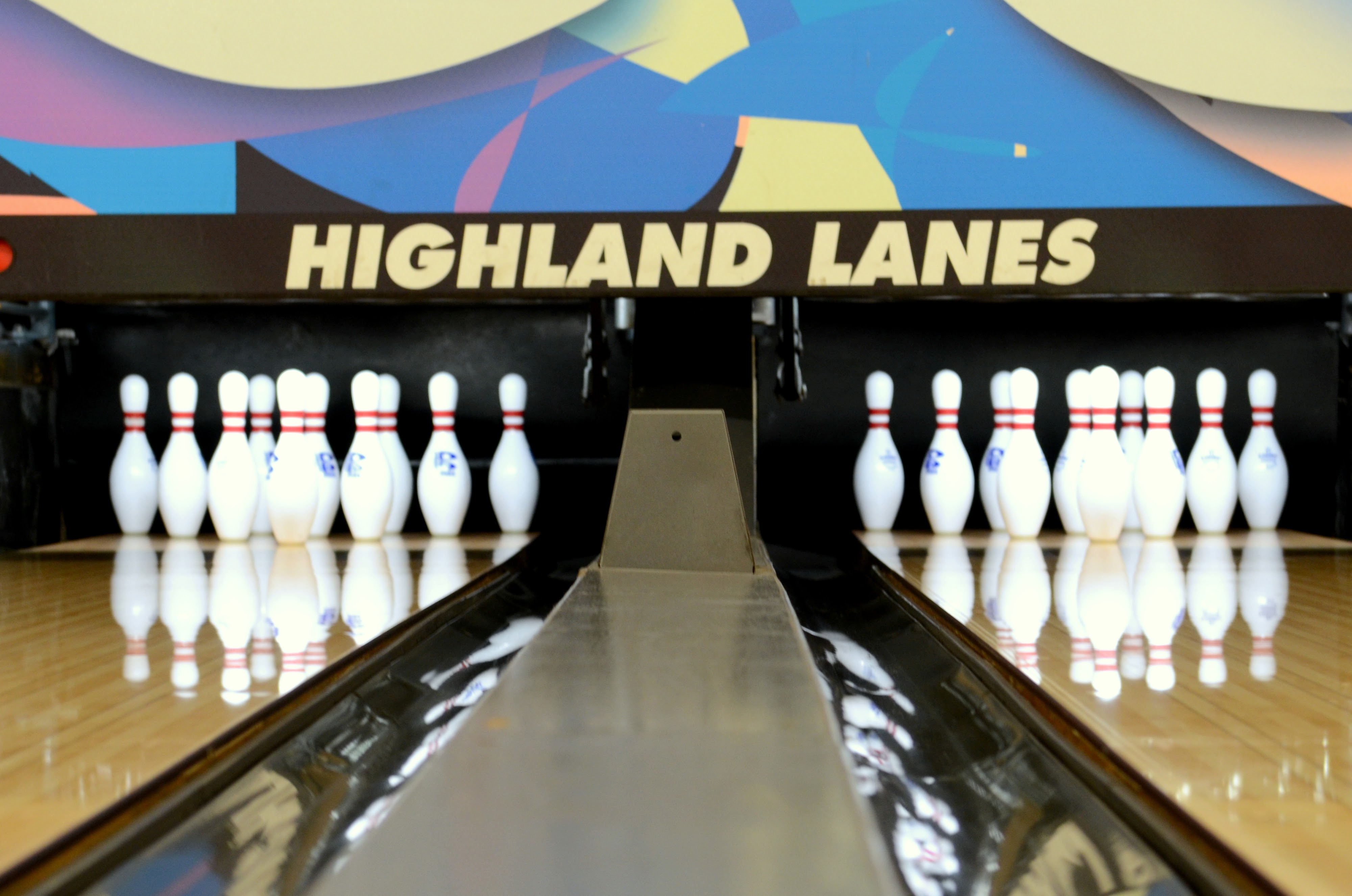 Low angle view of two bowling lanes with the Highland Lanes name displayed above the pins.