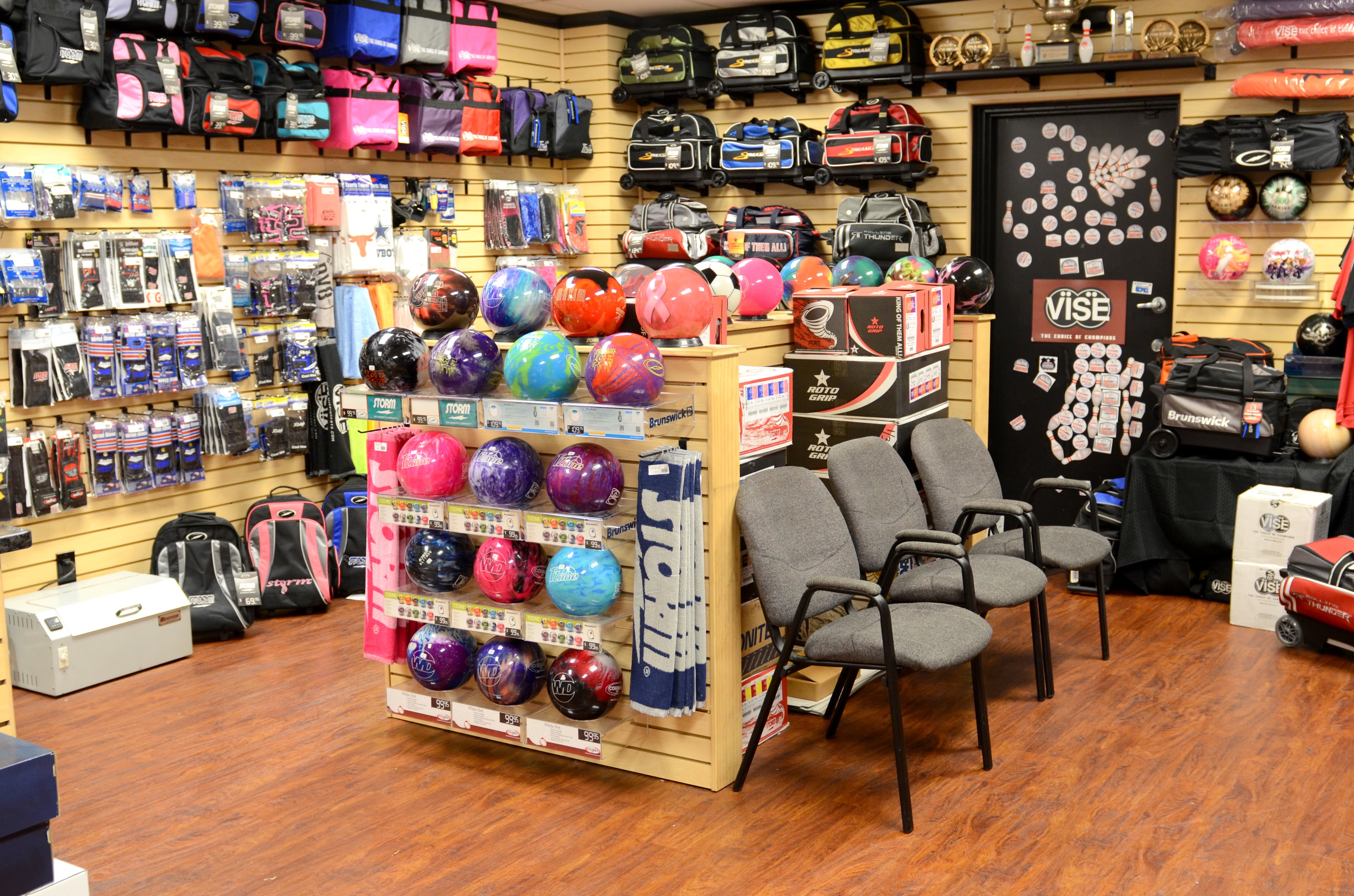 A well-stocked bowling pro shop with rows of colorful bowling balls, bags, and accessories on display.