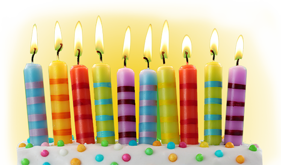 Ten colorful lit birthday candles on a white frosted cake with sprinkles.