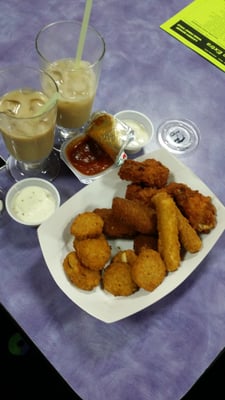 A platter of fried appetizers and two iced drinks on a purple table.