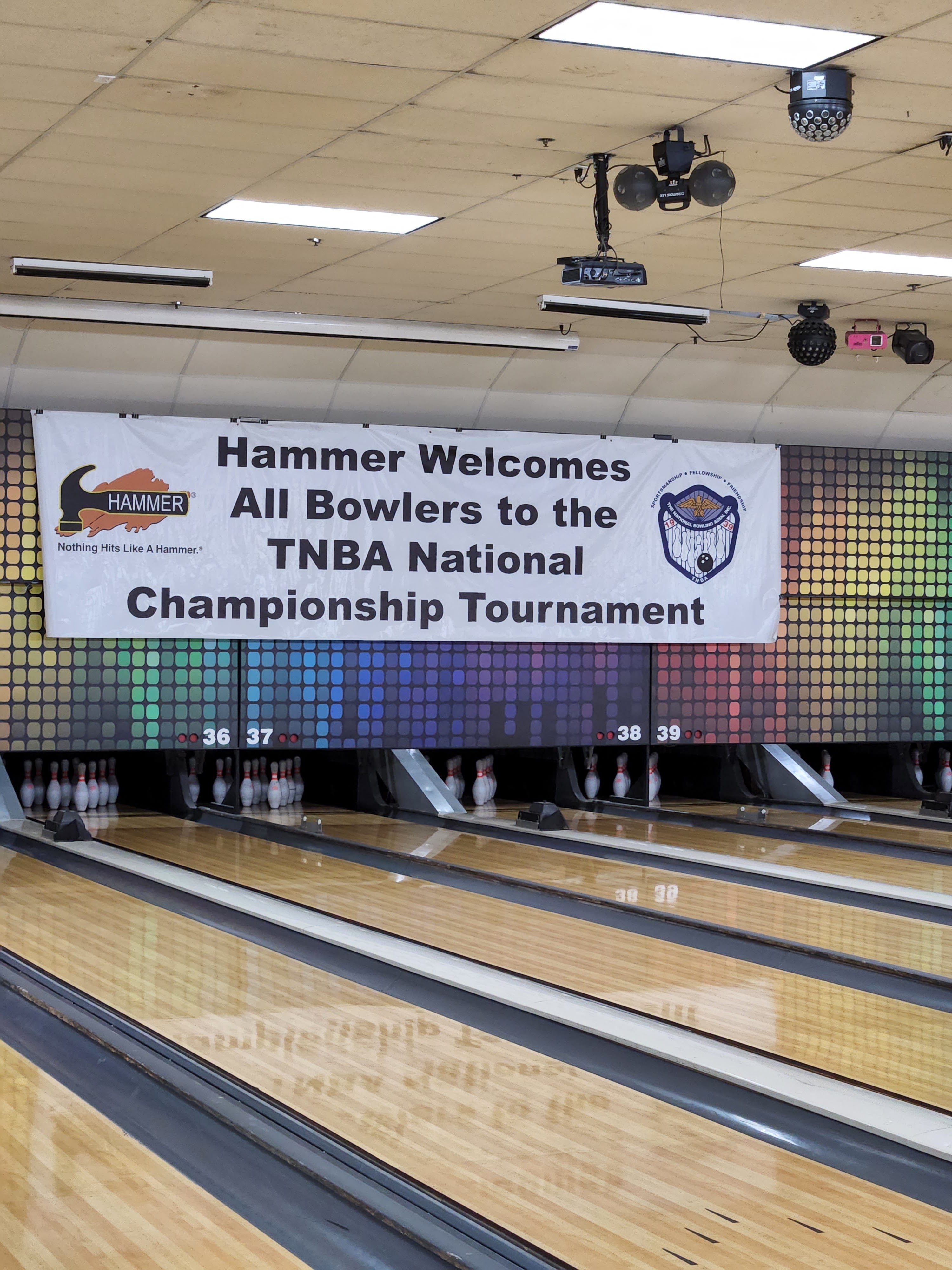 A bowling alley tournament banner welcoming TNBA National Championship participants above several lanes.
