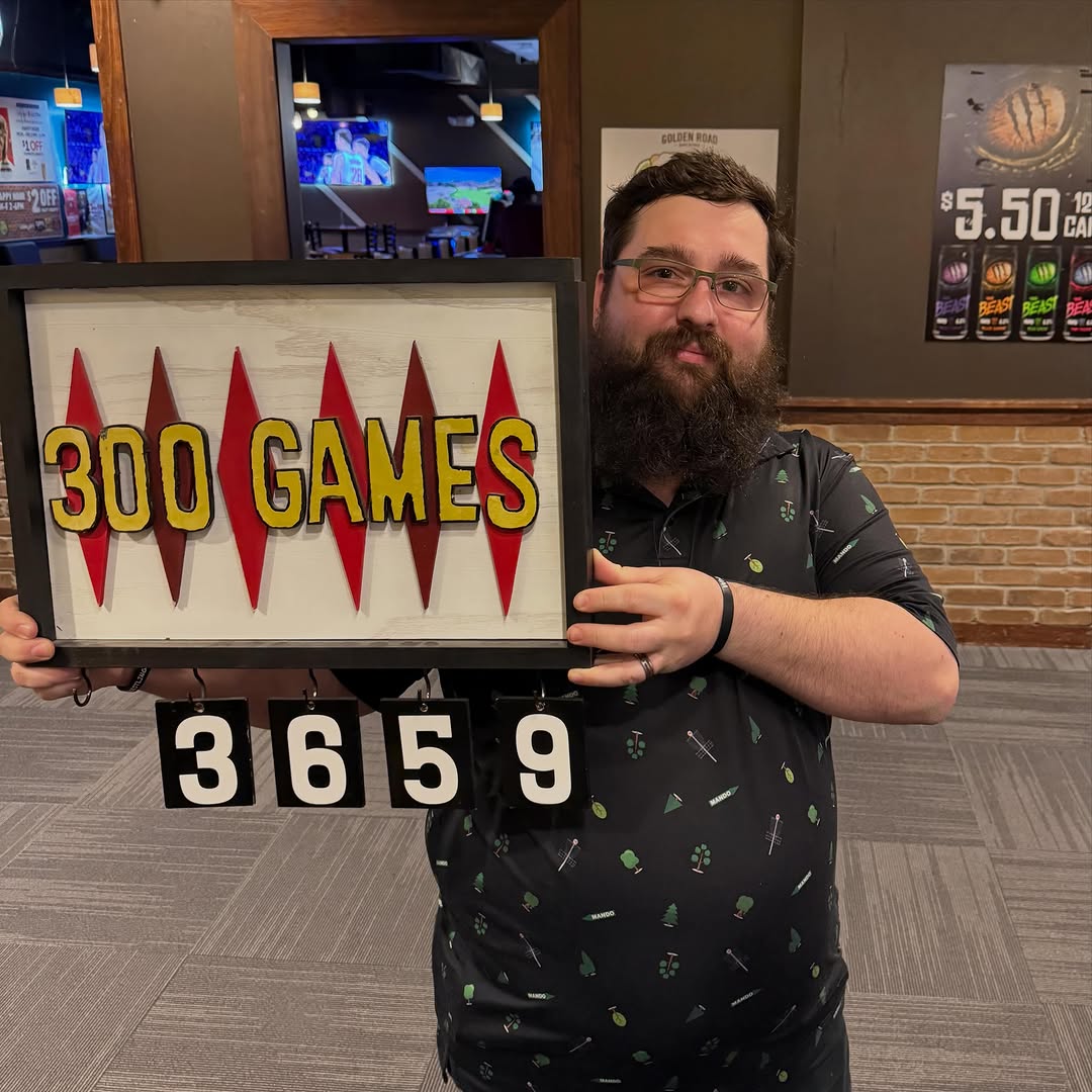 A man holding a commemorative sign that says 300 Games with a counter showing the number 3659.
