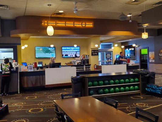 The main service counter and bowling ball racks inside a well-lit bowling center lobby.