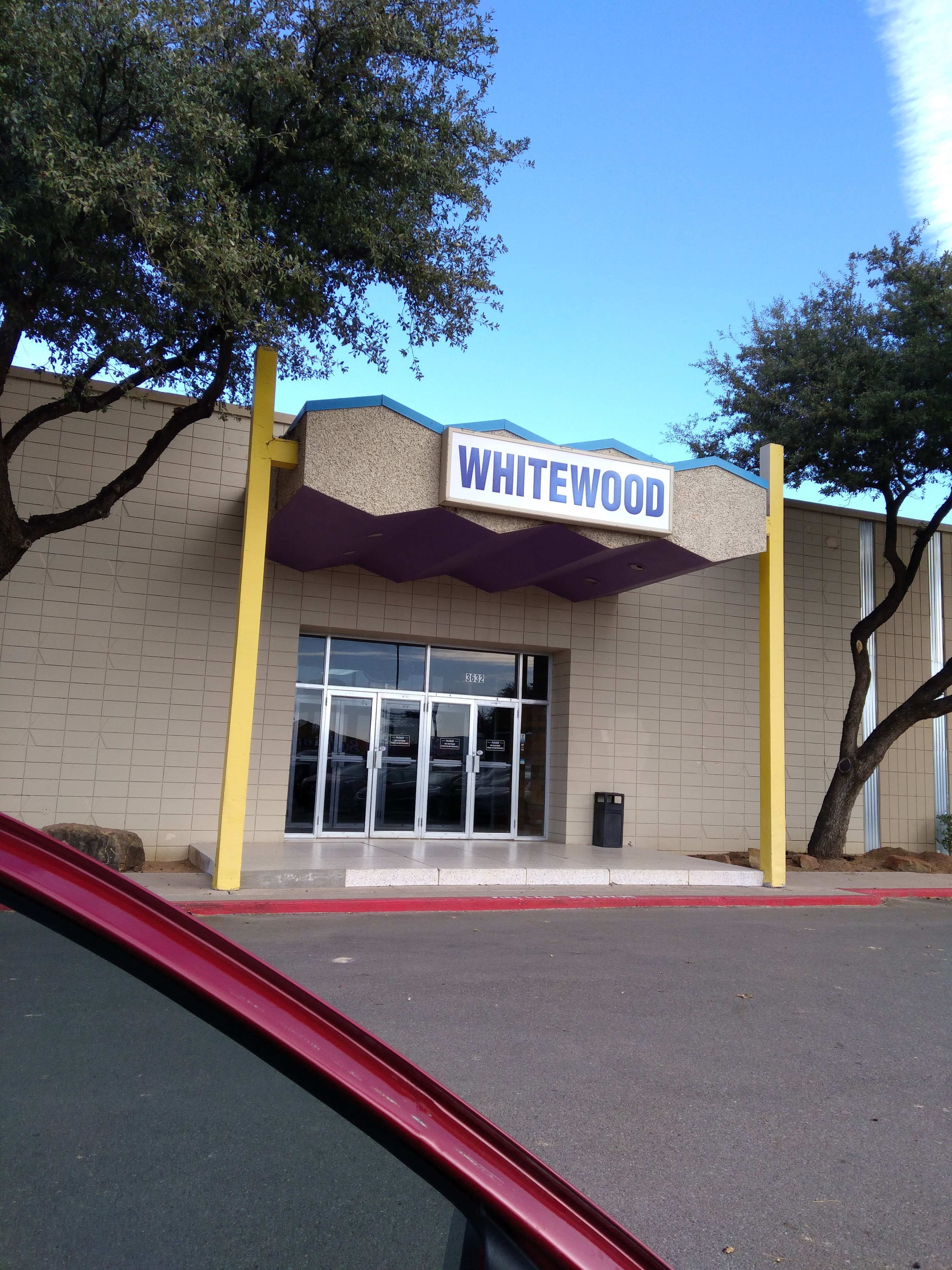 The exterior of Whitewood bowling center, showing the main entrance with a prominent sign and surrounding trees.