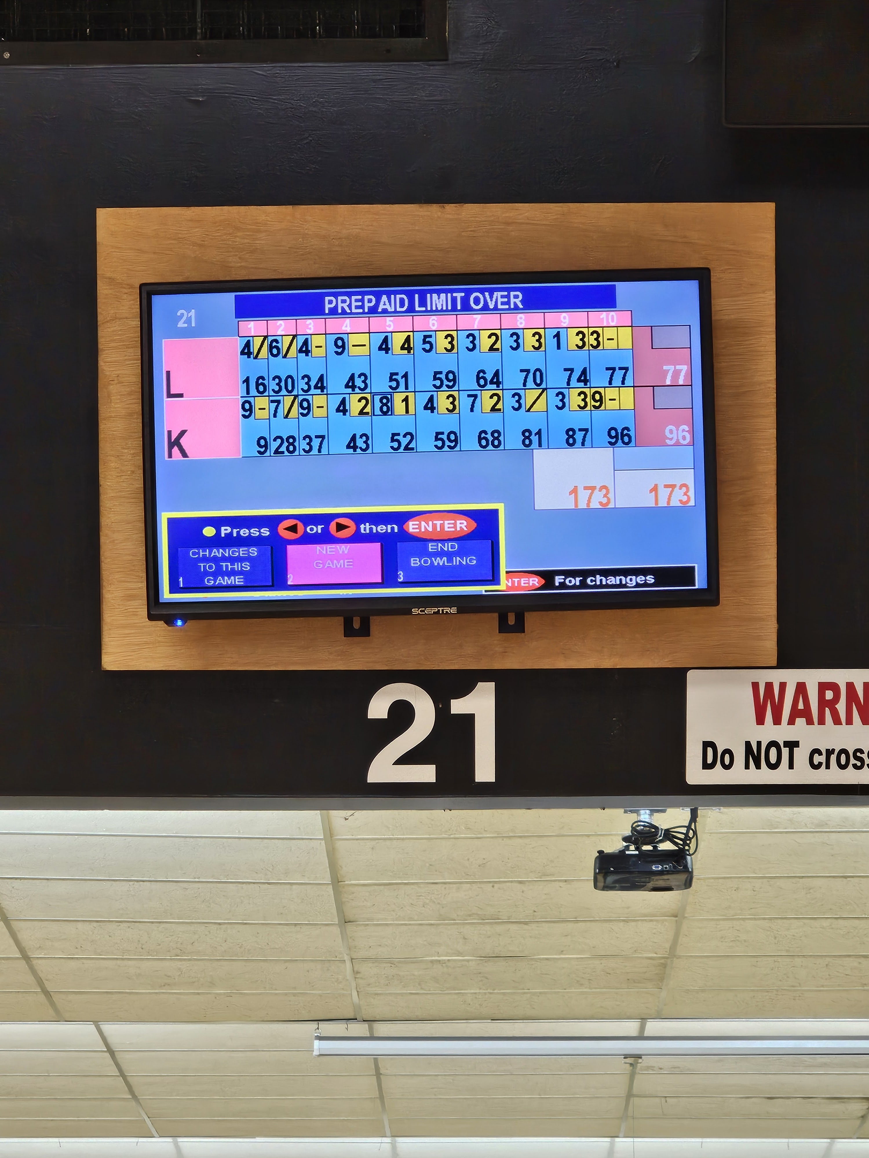 A bowling lane's automatic scoring screen for lane 21 shows scores for two players and input options.