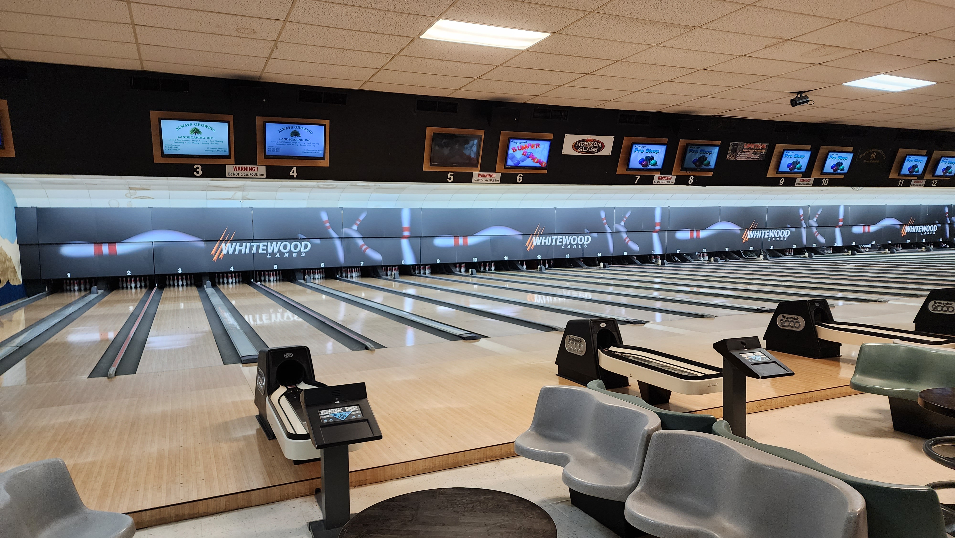 A wide shot of multiple bowling lanes at Whitewood Lanes-Lubbock, showing the pin setters, overhead scoring screens, and bowler seating.