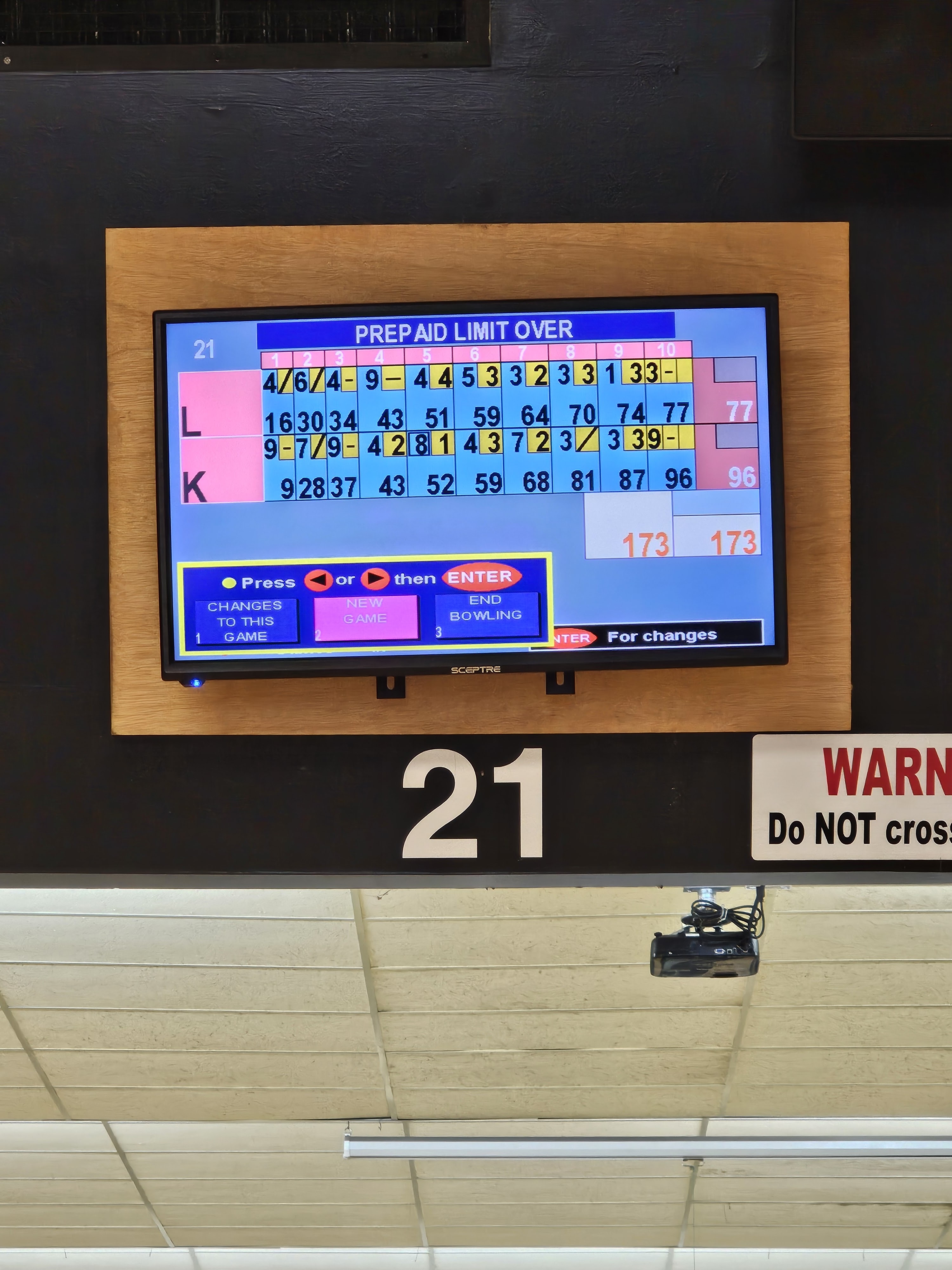 A close-up of a bowling lane's automatic scoring screen showing scores for two players and game options.