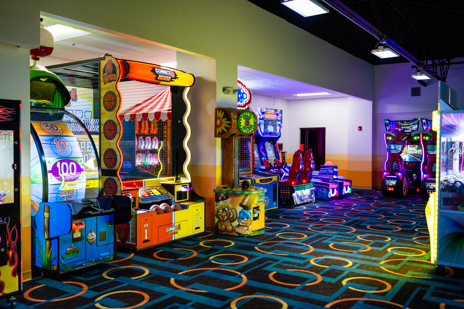 A colorful arcade room with various ticket redemption games and a patterned carpet.