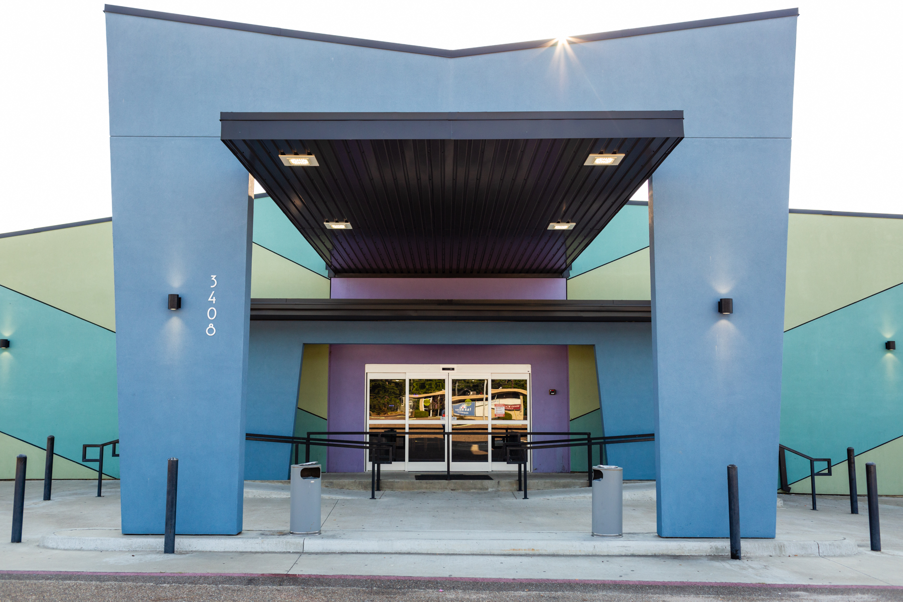 Exterior view of the colorful Holiday Entertainment building entrance with a large blue portico and accessible ramps.