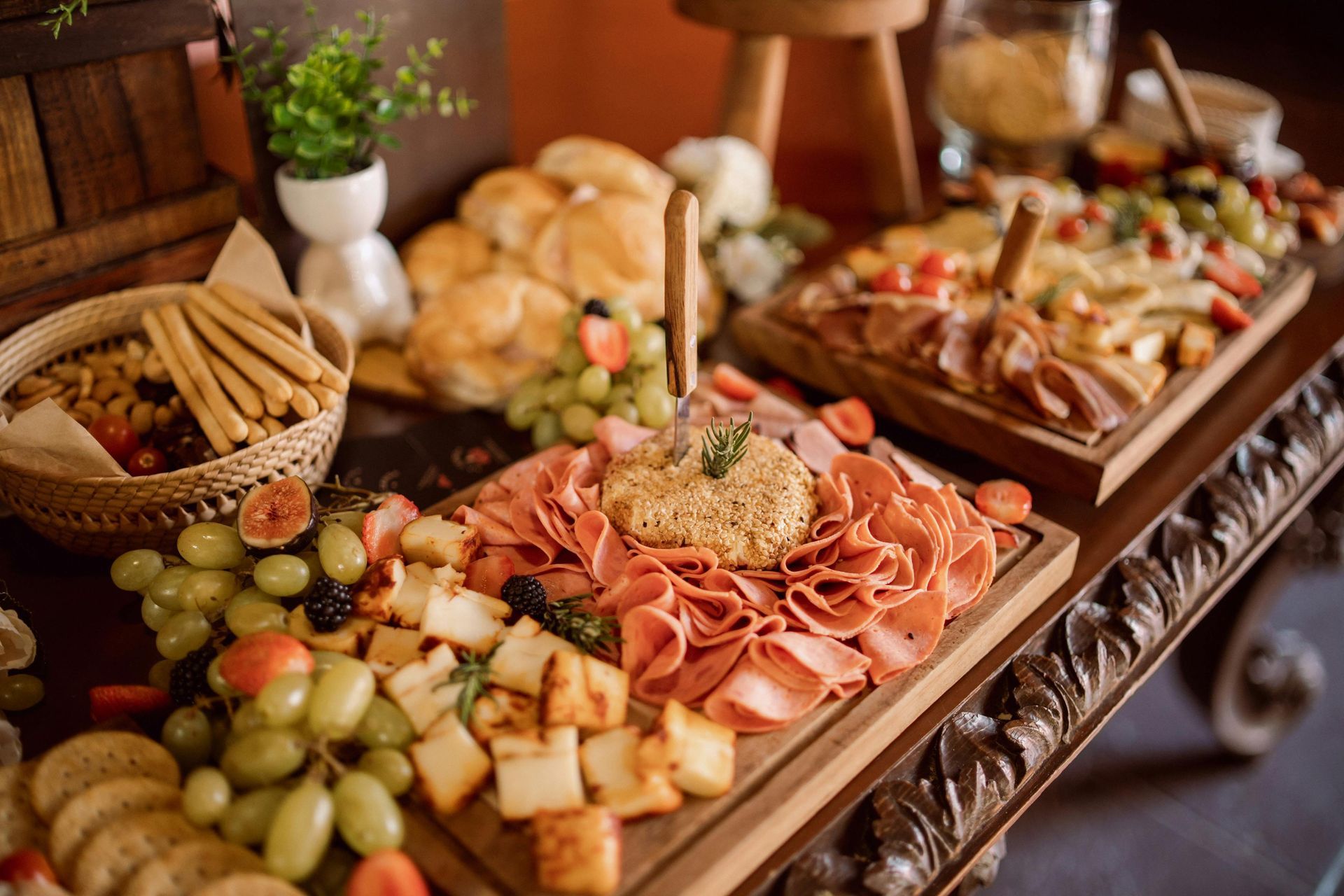 A variety of charcuterie boards featuring meats, cheeses, grapes, and berries on wooden platters.