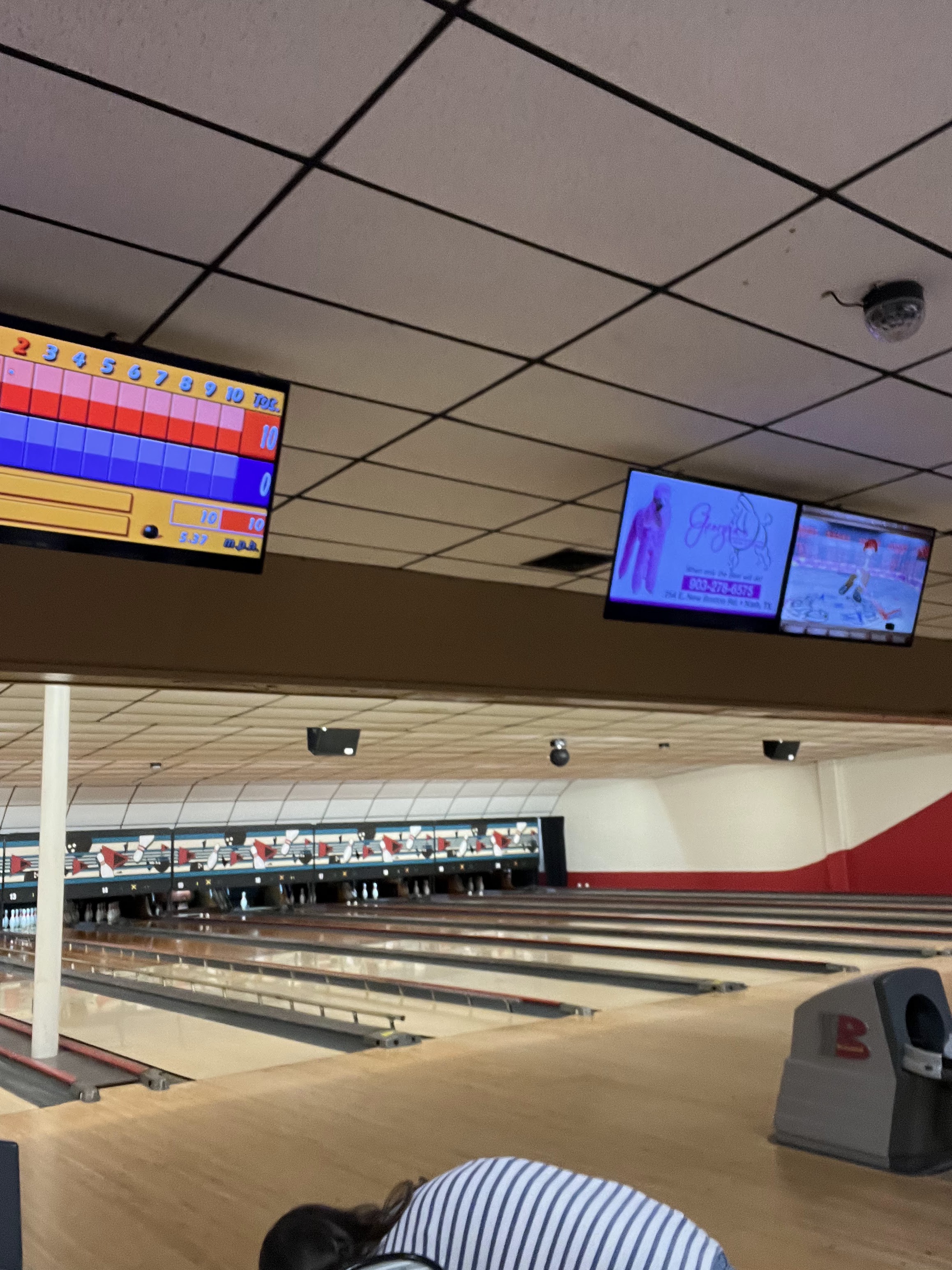 Interior of a bowling alley with wooden lanes, overhead scoring monitors, and deployed bumper rails.