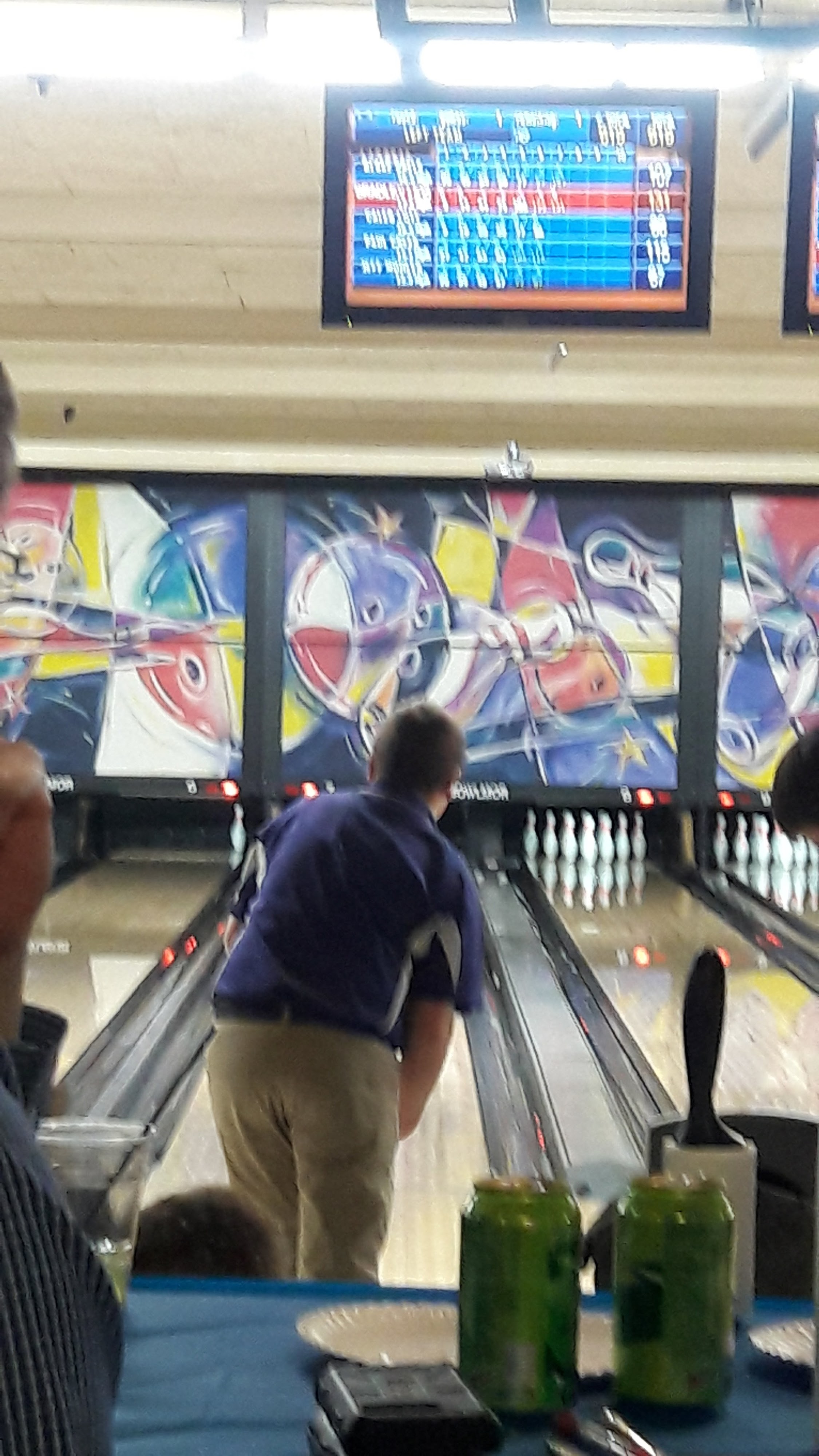 A bowler in a blue shirt prepares to throw a ball down a lane at Bowlmor Lanes.