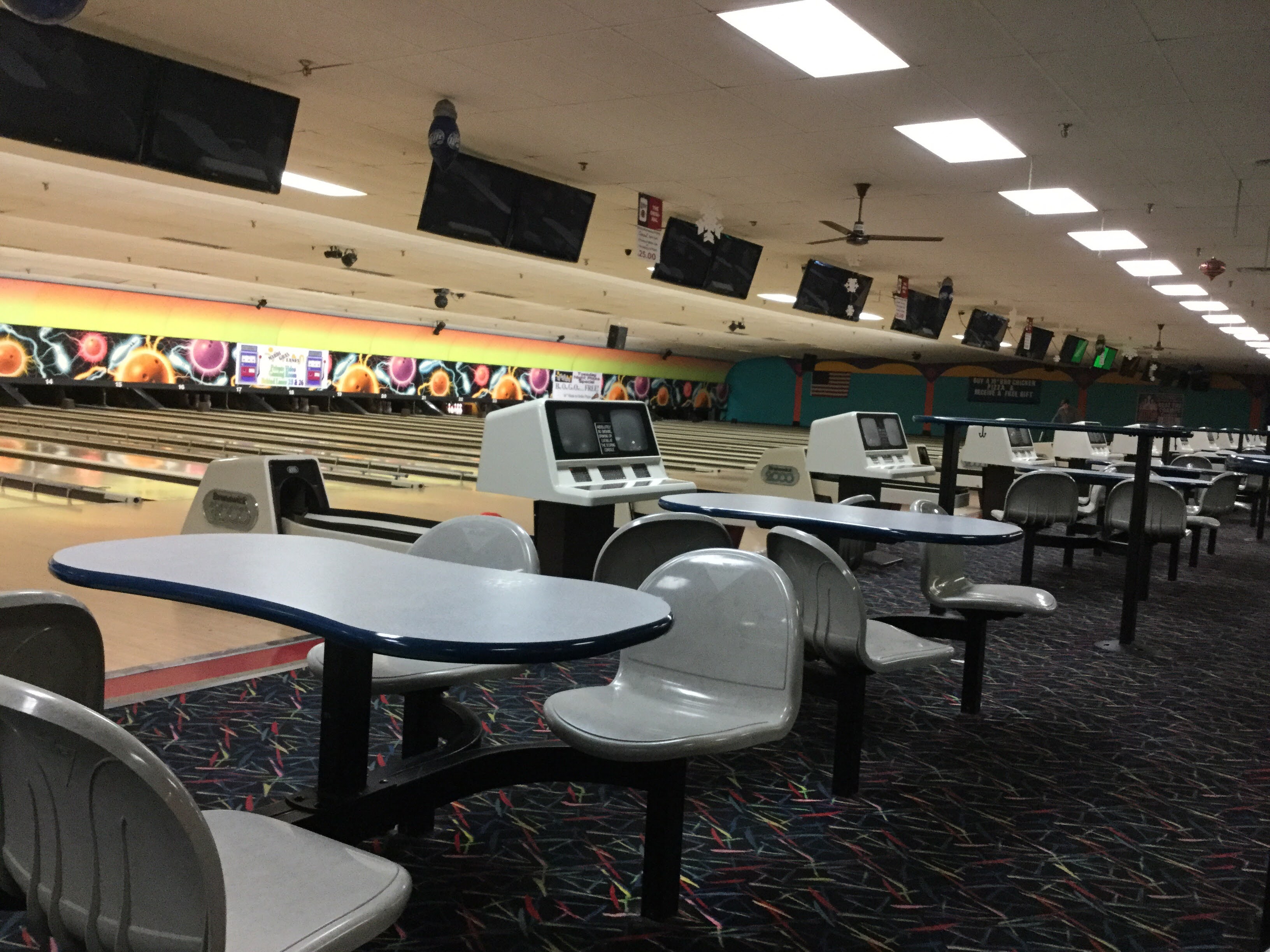 Empty bowling alley interior showing the seating area and several lanes with colorful backdrops.