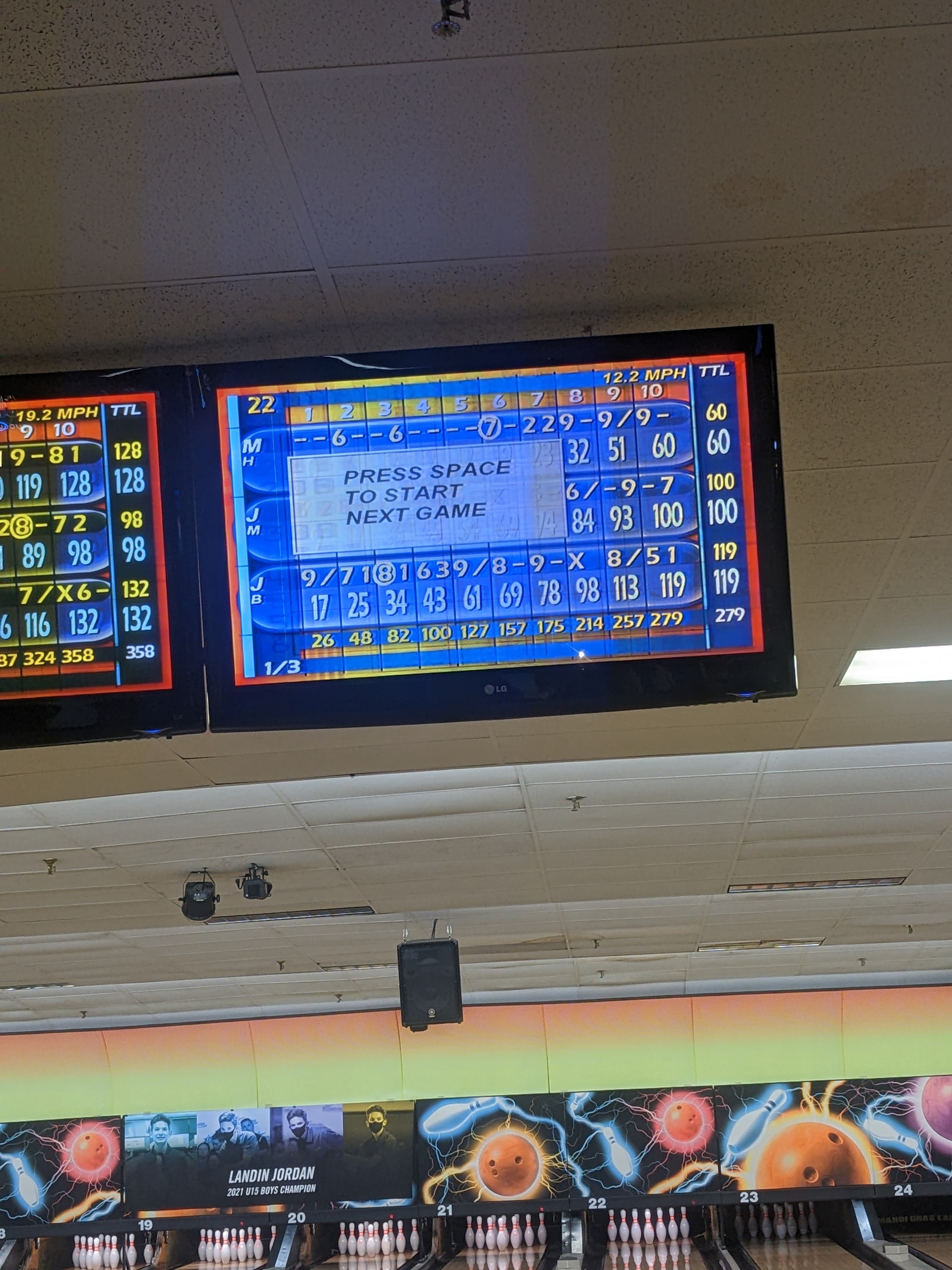 Overhead bowling score monitors showing a 279 high score above the lanes.