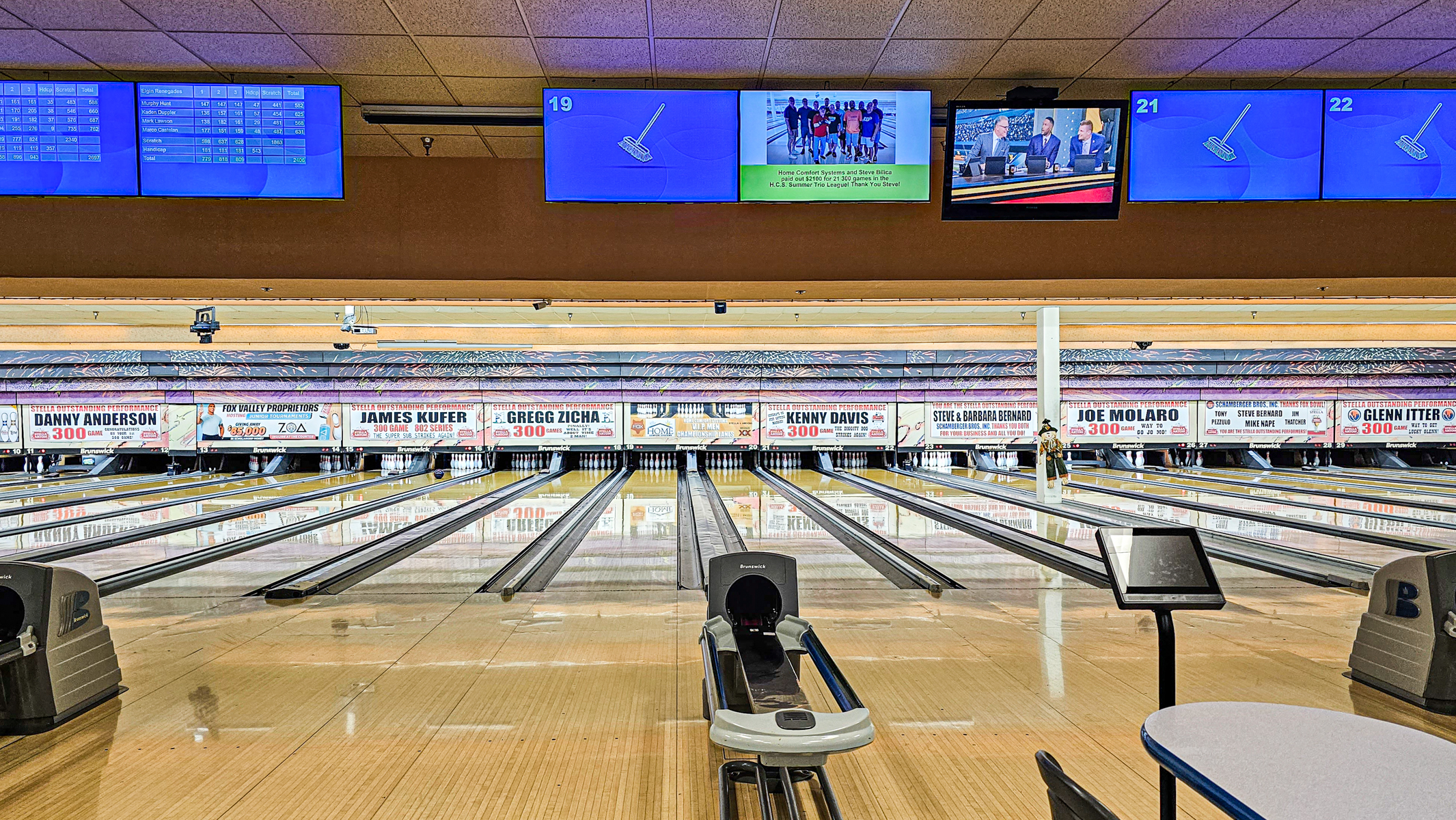 A wide view of polished bowling lanes at Fox Bowl with league recognition banners and overhead score monitors.