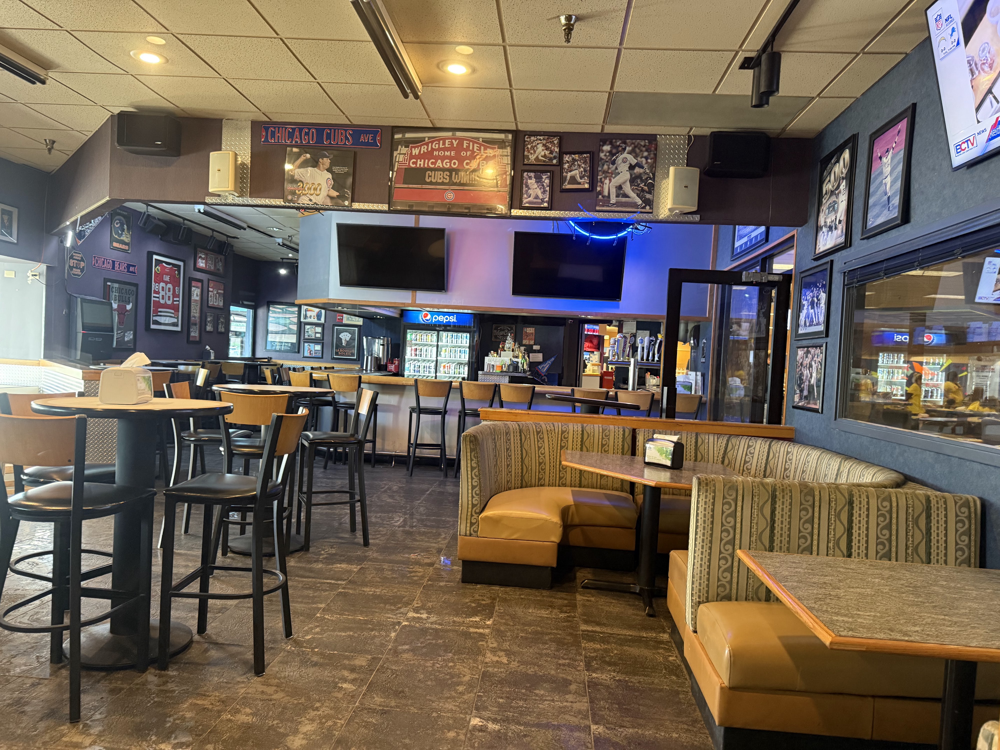 Interior of a sports bar with booths, high-top tables, and Chicago sports memorabilia on the walls.