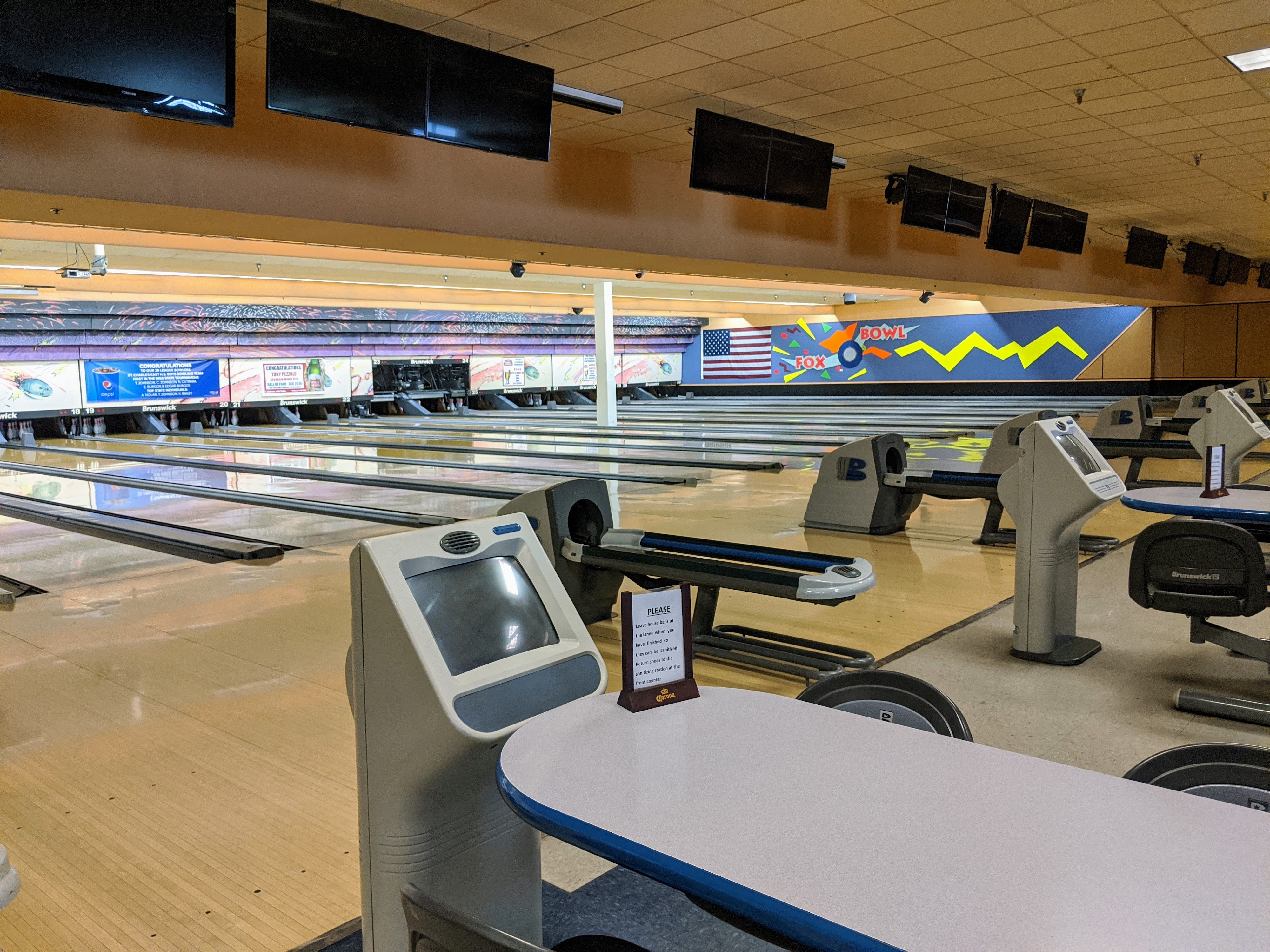 A clean and well-lit interior view of multiple bowling lanes with scoring consoles at Fox Bowl.