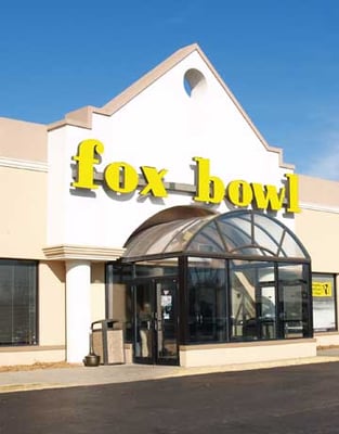 The exterior of Fox Bowl featuring yellow signage and a glass dome entrance under a blue sky.