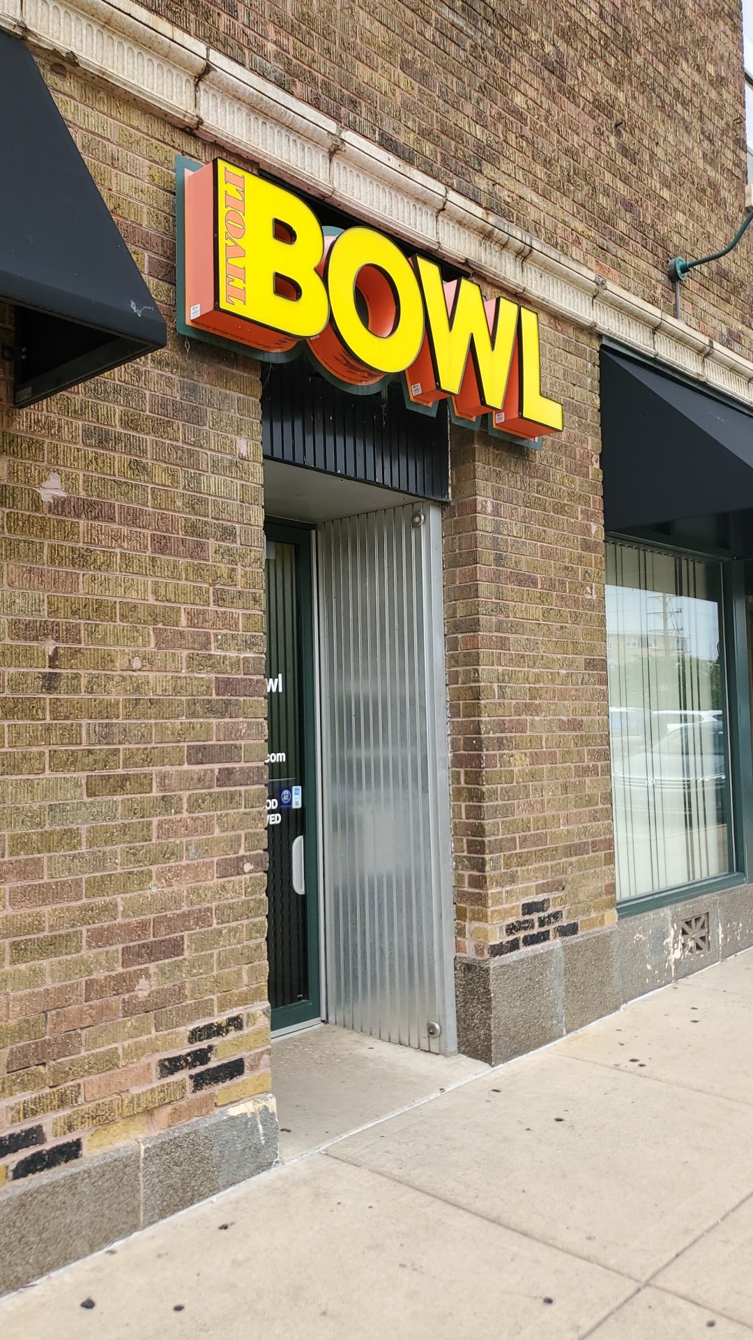 A vertical view of the brick exterior and yellow Tivoli Bowl sign above the entrance.