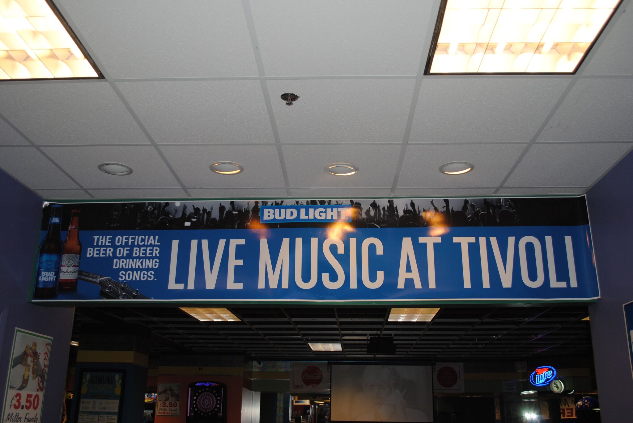 A blue banner hanging from a ceiling reads Live Music at Tivoli with Bud Light branding.