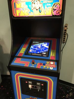 A classic blue Ms. Pac-Man arcade game cabinet standing against a wall in a game room.