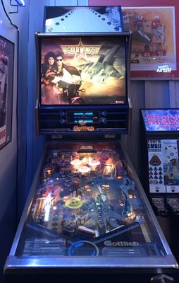 A vintage Gold Wings pinball machine by Gottlieb standing in an arcade area.