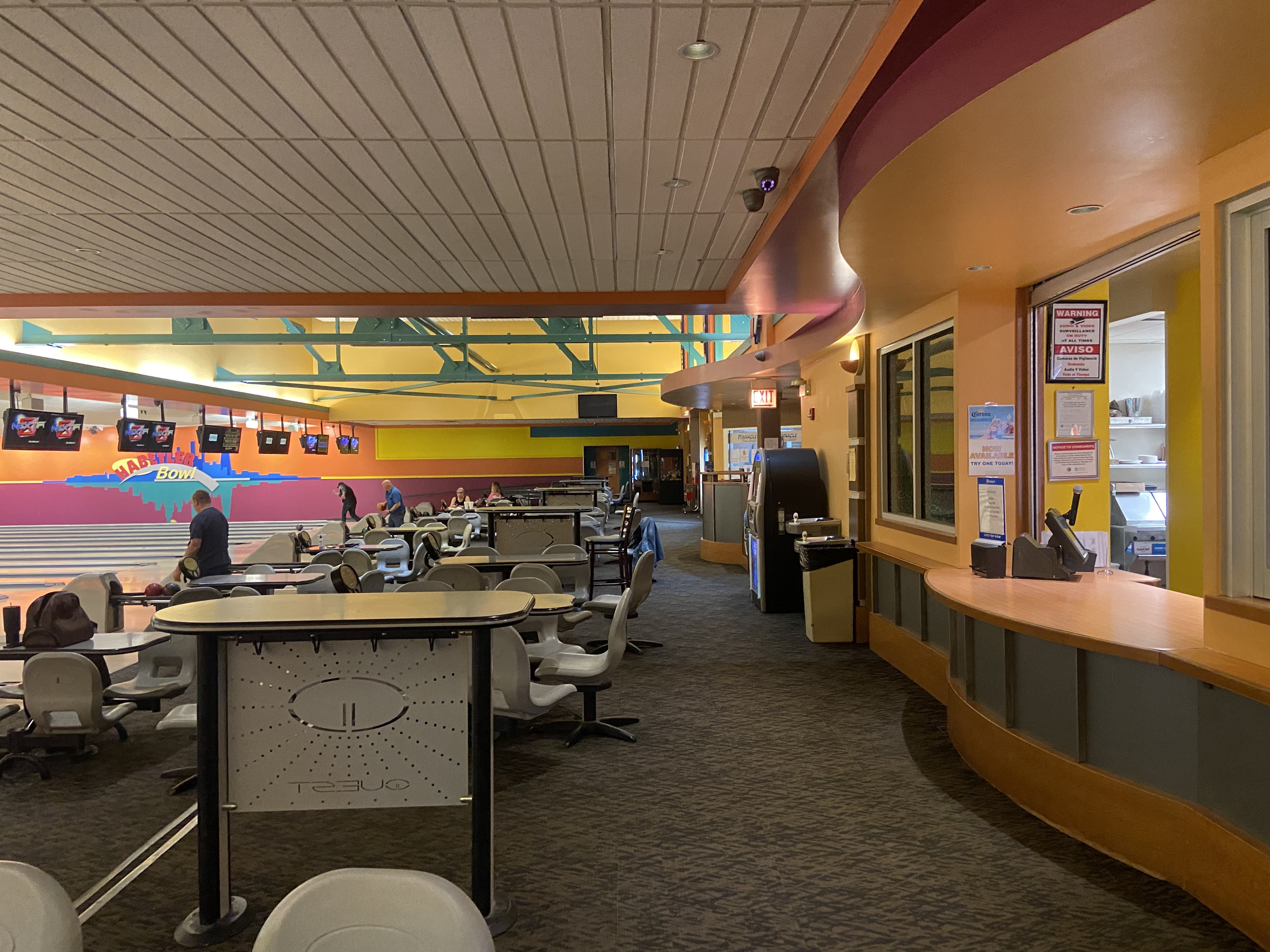 An interior view of a bowling alley showing the service counter, spectator seating, and lanes in the distance.