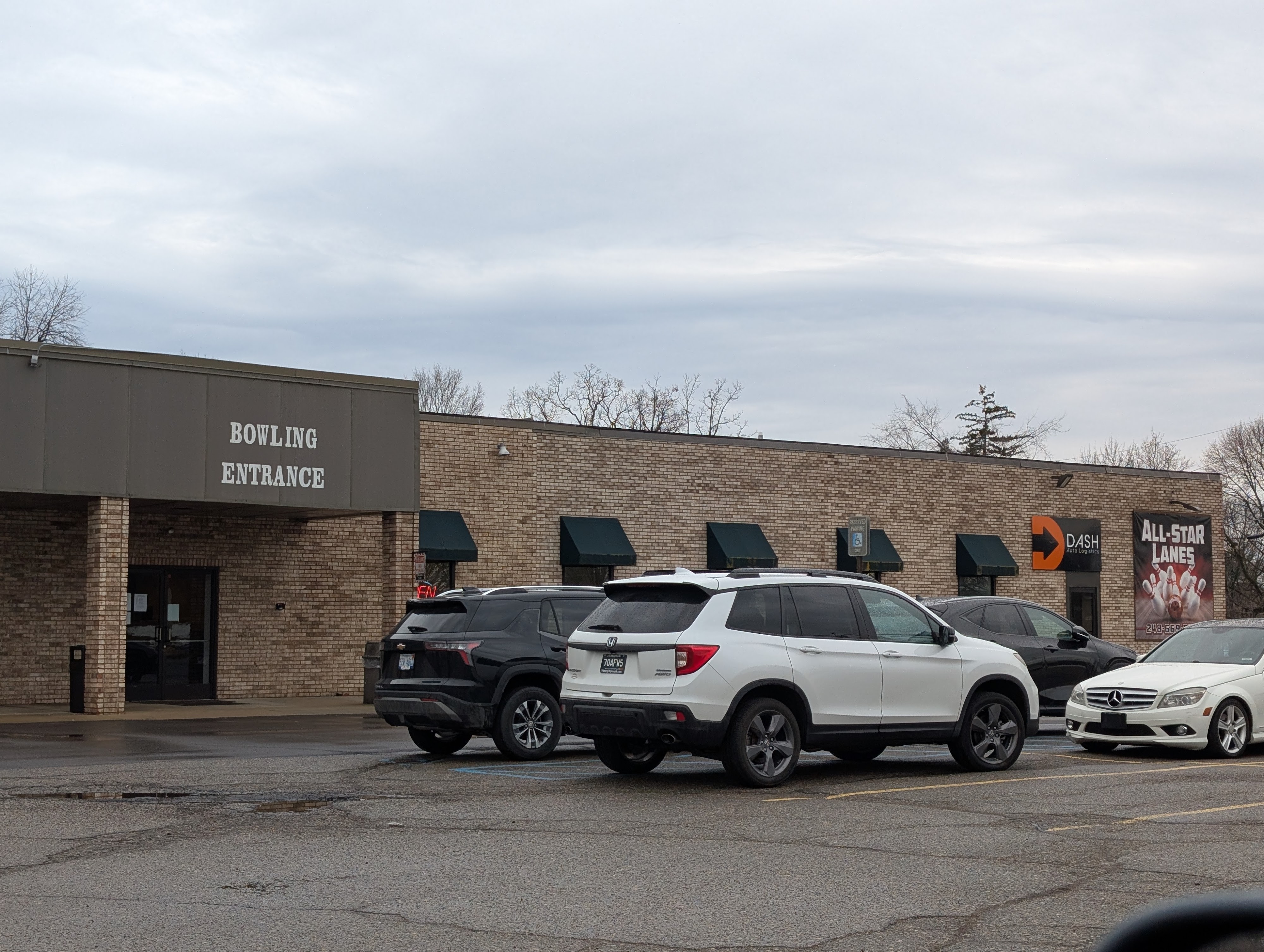 Exterior of All Star Lanes bowling center with a brick facade and parked cars in the lot.