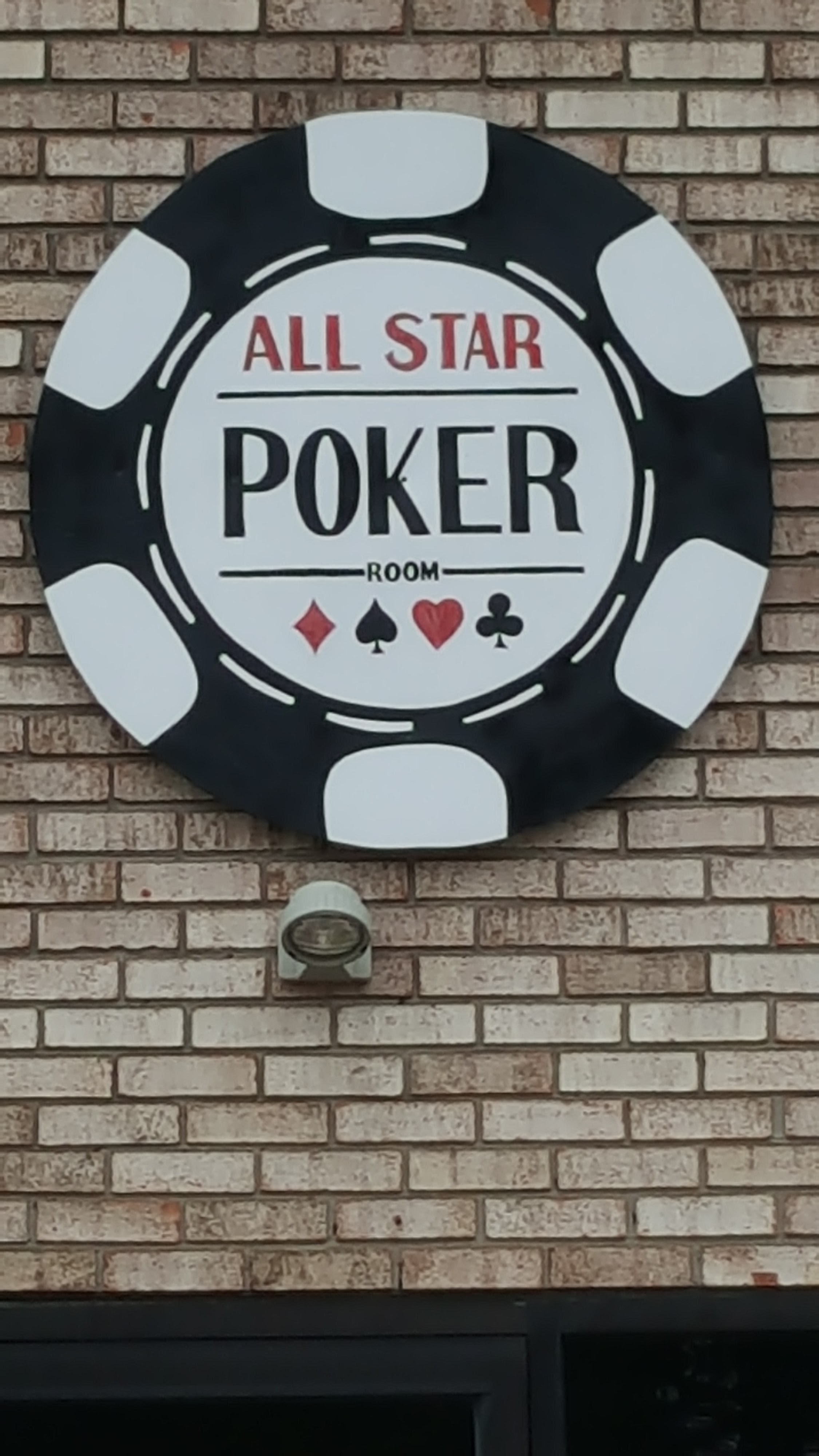 A circular poker chip sign for the All Star Poker Room mounted on a brick wall.