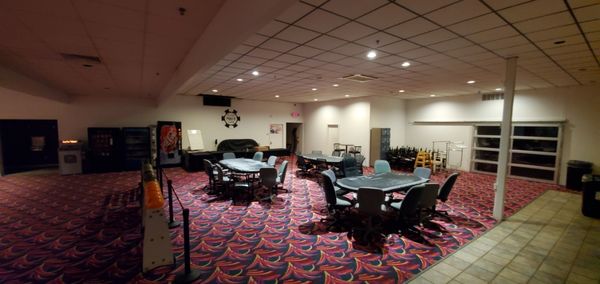 A carpeted multi-purpose room with three large oval card tables and rolling chairs.
