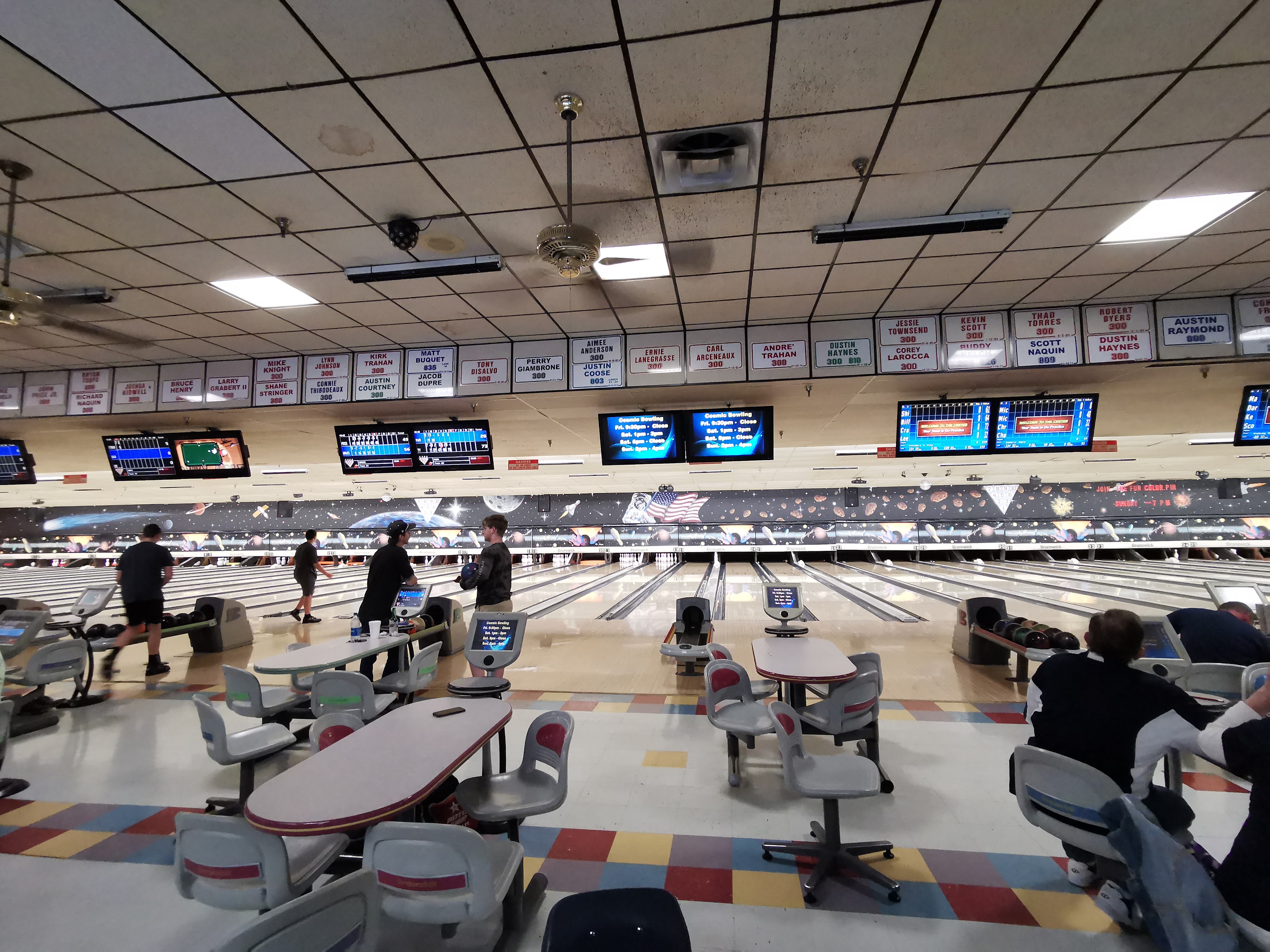 A wide view of the bowling lanes and seating area at Creole Lanes with bowlers mid-game.