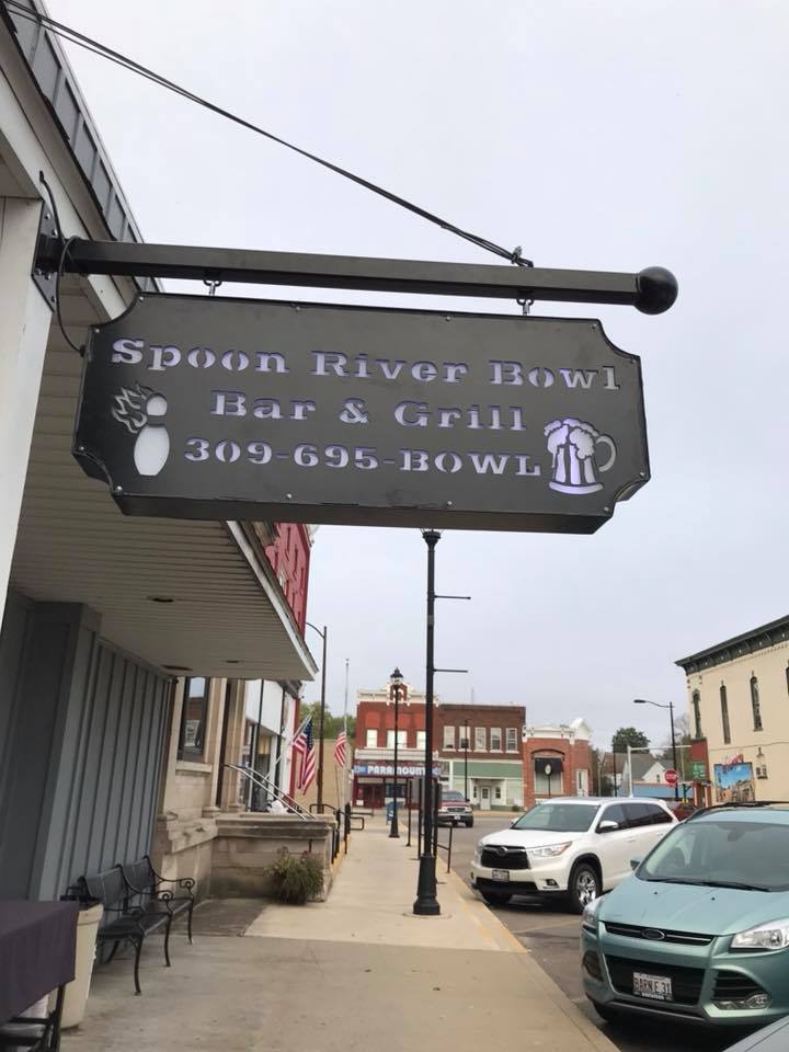A black hanging sign with "Spoon River Bowl Bar & Grill" and phone number 309-695-BOWL.